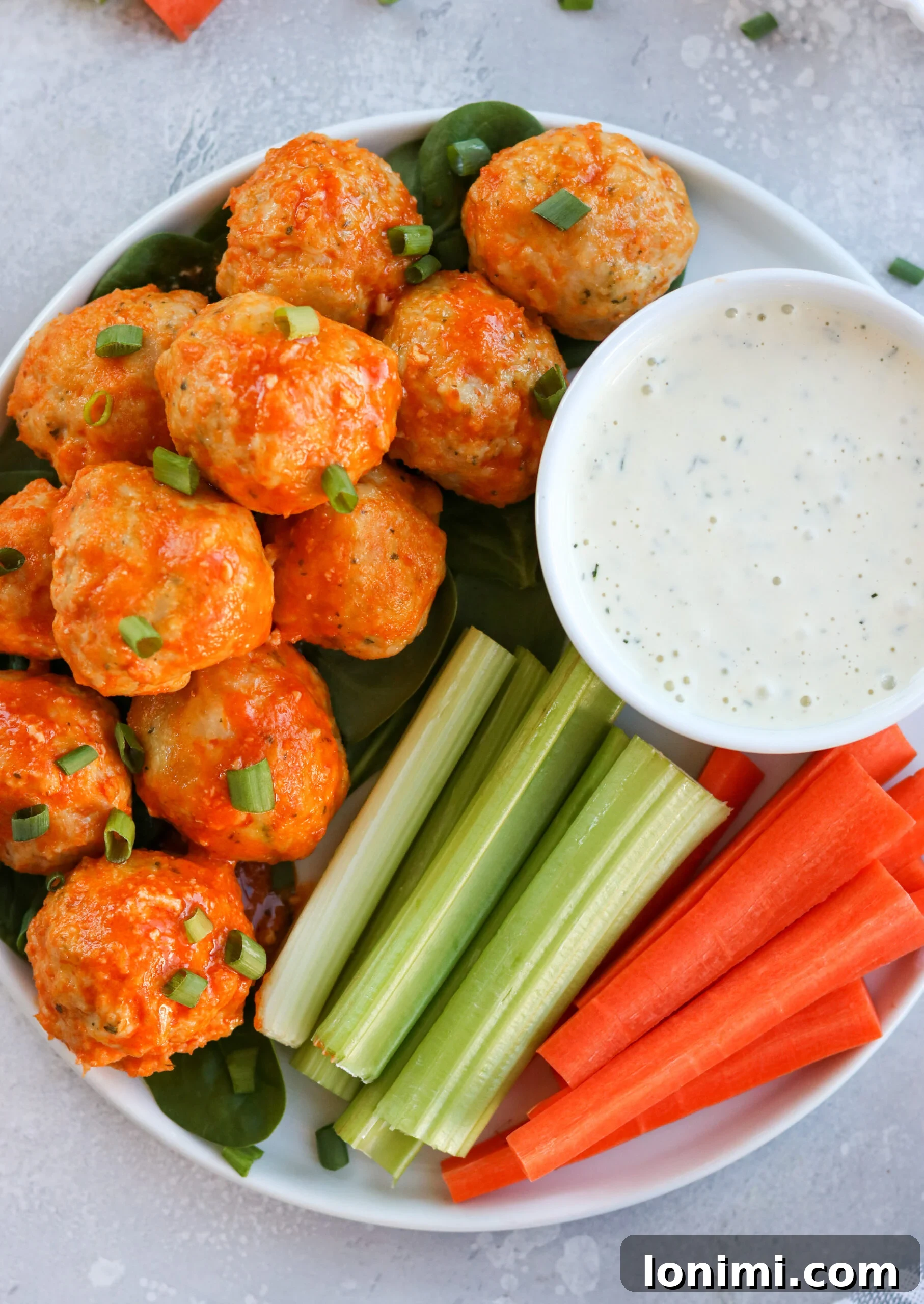 Juicy buffalo chicken meatballs topped with fresh parsley and a side of creamy ranch dressing, perfect for game day