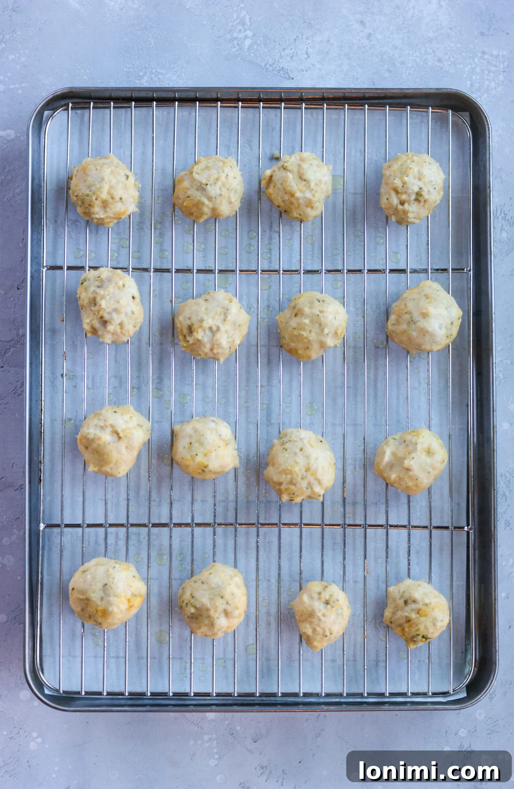 Baked buffalo chicken meatballs arranged on a baking sheet, showcasing their golden-brown texture before saucing