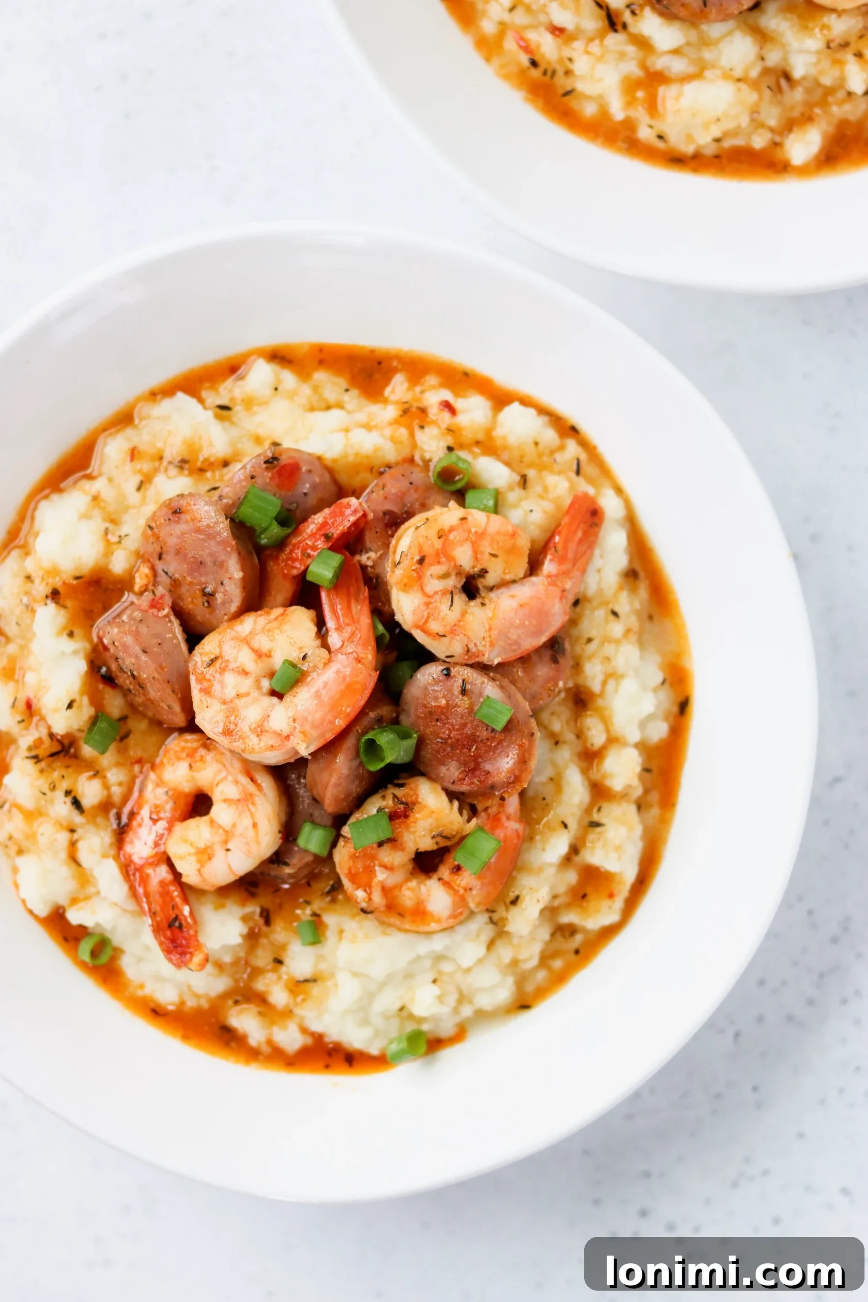Keto shrimp and cauliflower grits with sausage in a white bowl