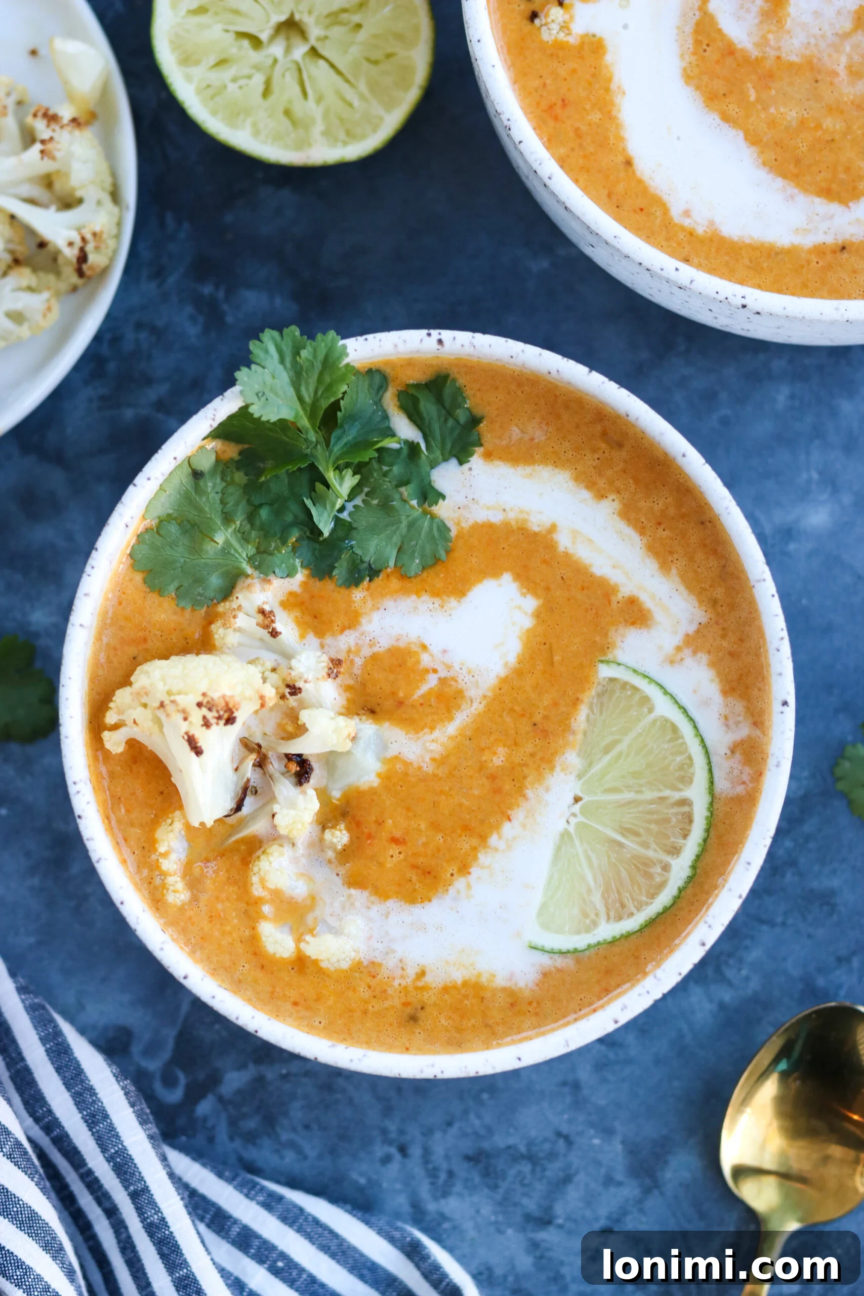 Rich and creamy Curried Cauliflower Carrot Soup in a white bowl, garnished with fresh cilantro.