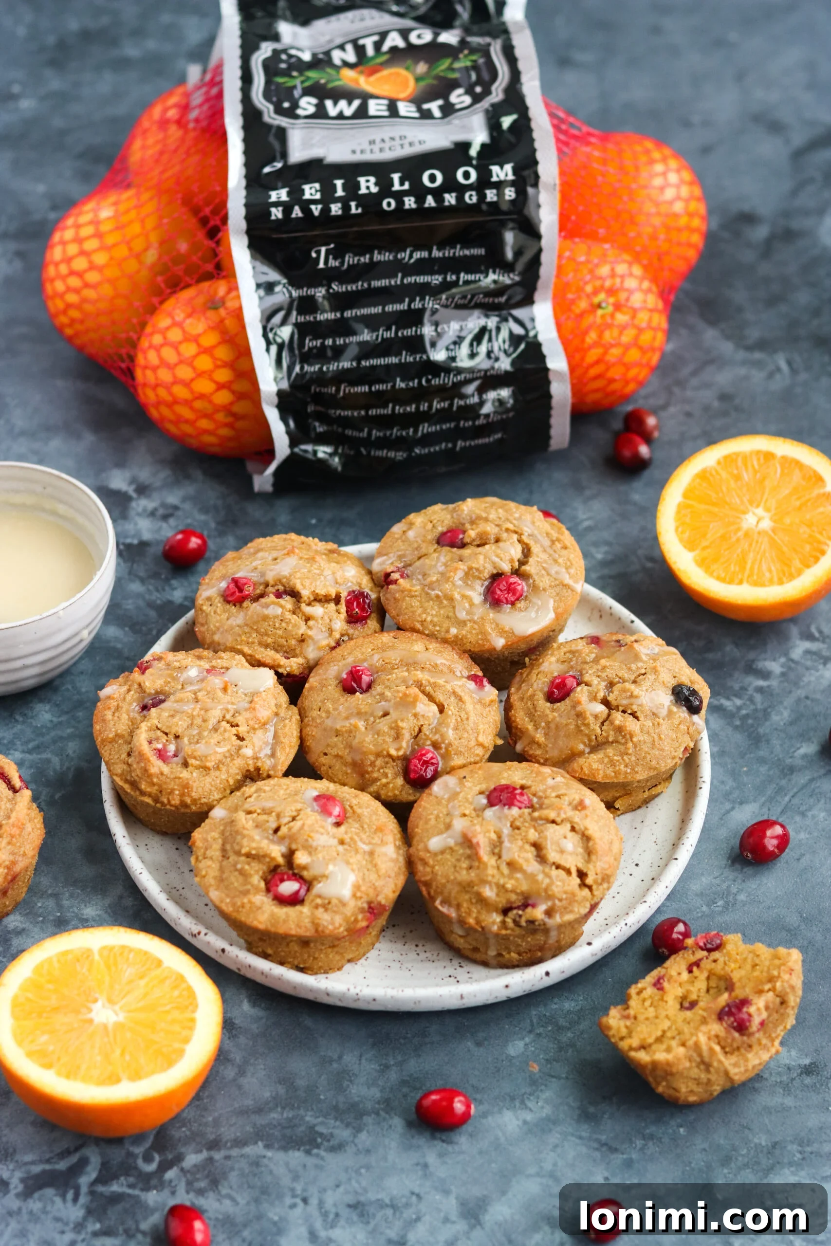 Delicious and healthy Cranberry Orange Muffins A close-up shot of Paleo Cranberry Orange Muffins on a white plate, artfully surrounded by fresh orange segments, emphasizing the citrus notes in the recipe.
