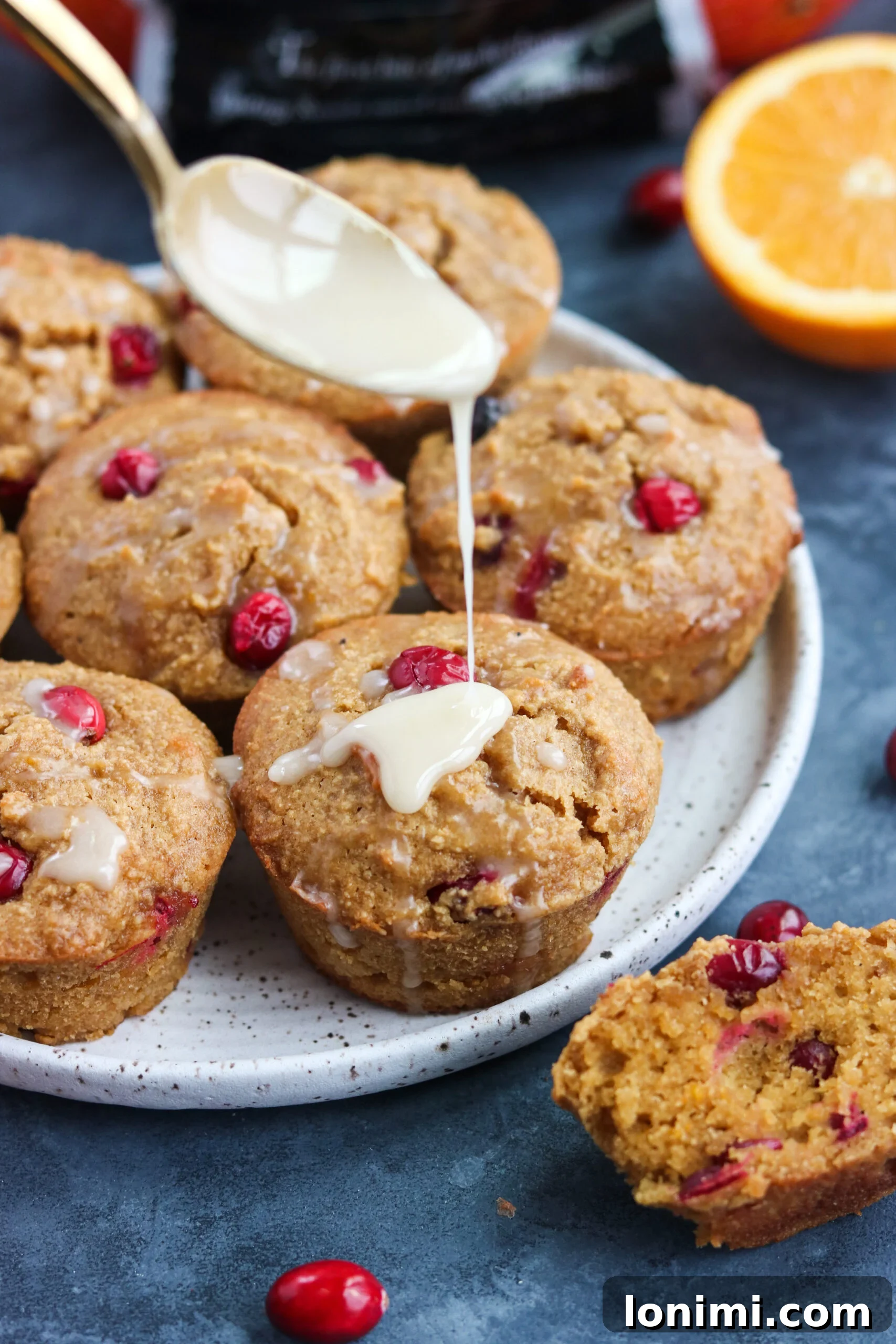 Adding finishing touches to Paleo Cranberry Orange Muffins A person gently adding a sprinkle of orange zest or sugar glaze to the tops of freshly baked Paleo Orange Cranberry Muffins.