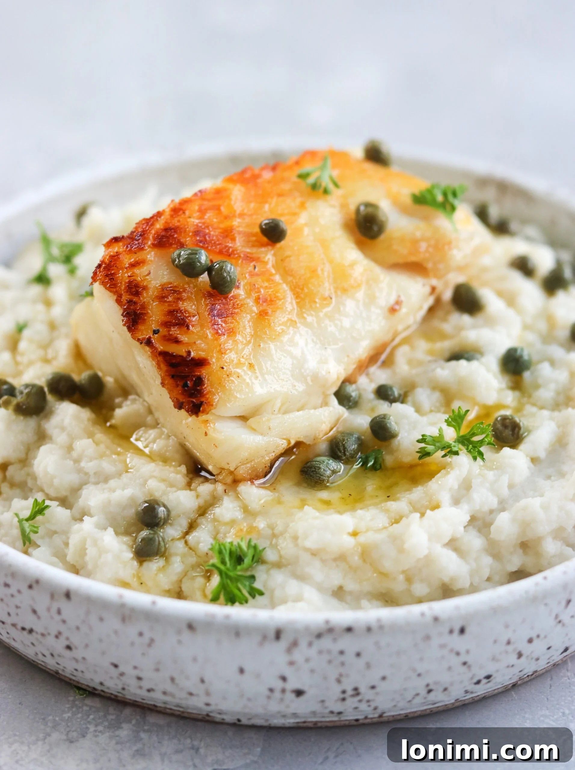 Pan Seared Chilean Sea Bass with Lemon Caper Butter on a beautiful serving dish, ready to be enjoyed.