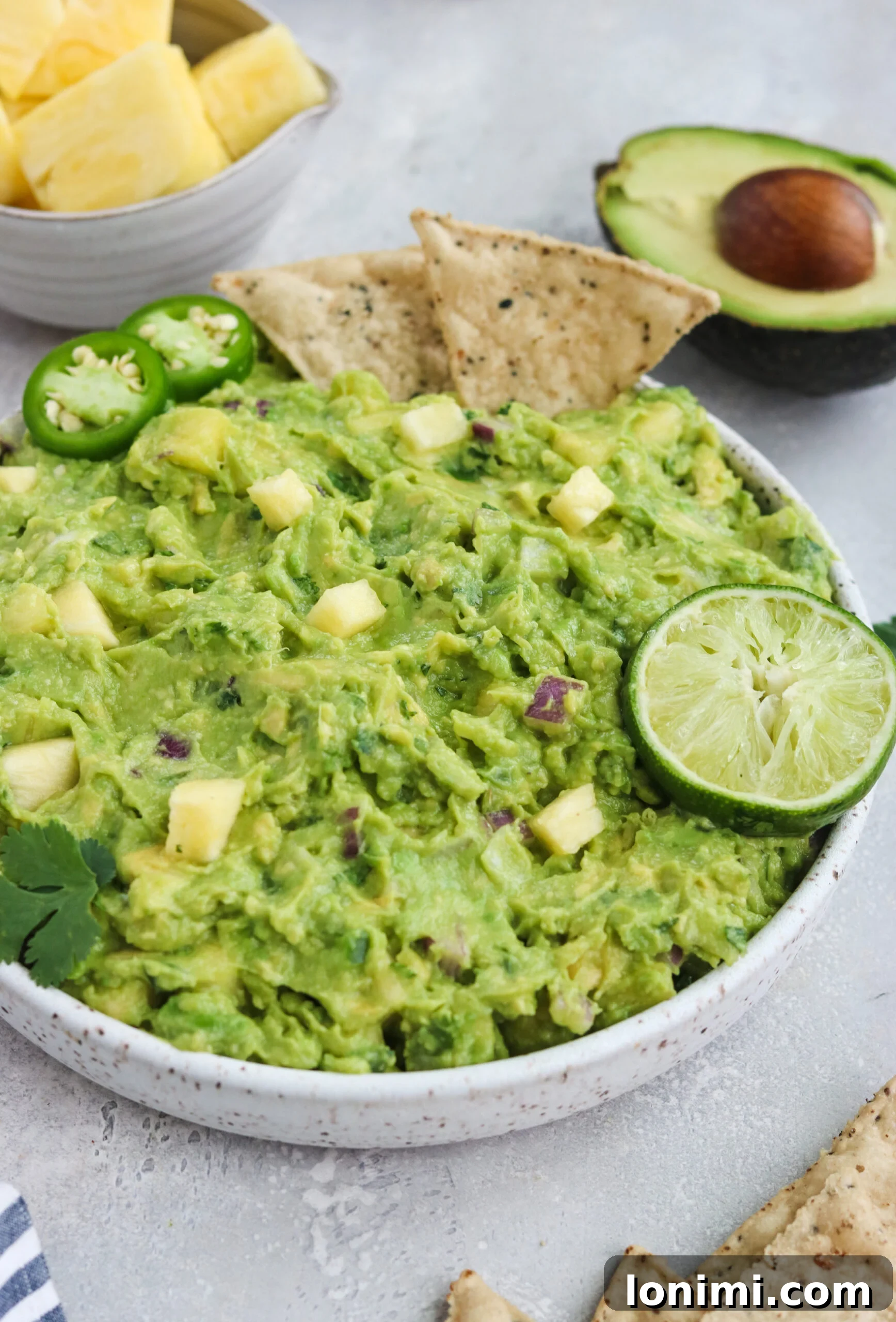 A bowl of creamy Paleo Pineapple Guacamole with avocado slices, pineapple chunks, and a hint of cilantro