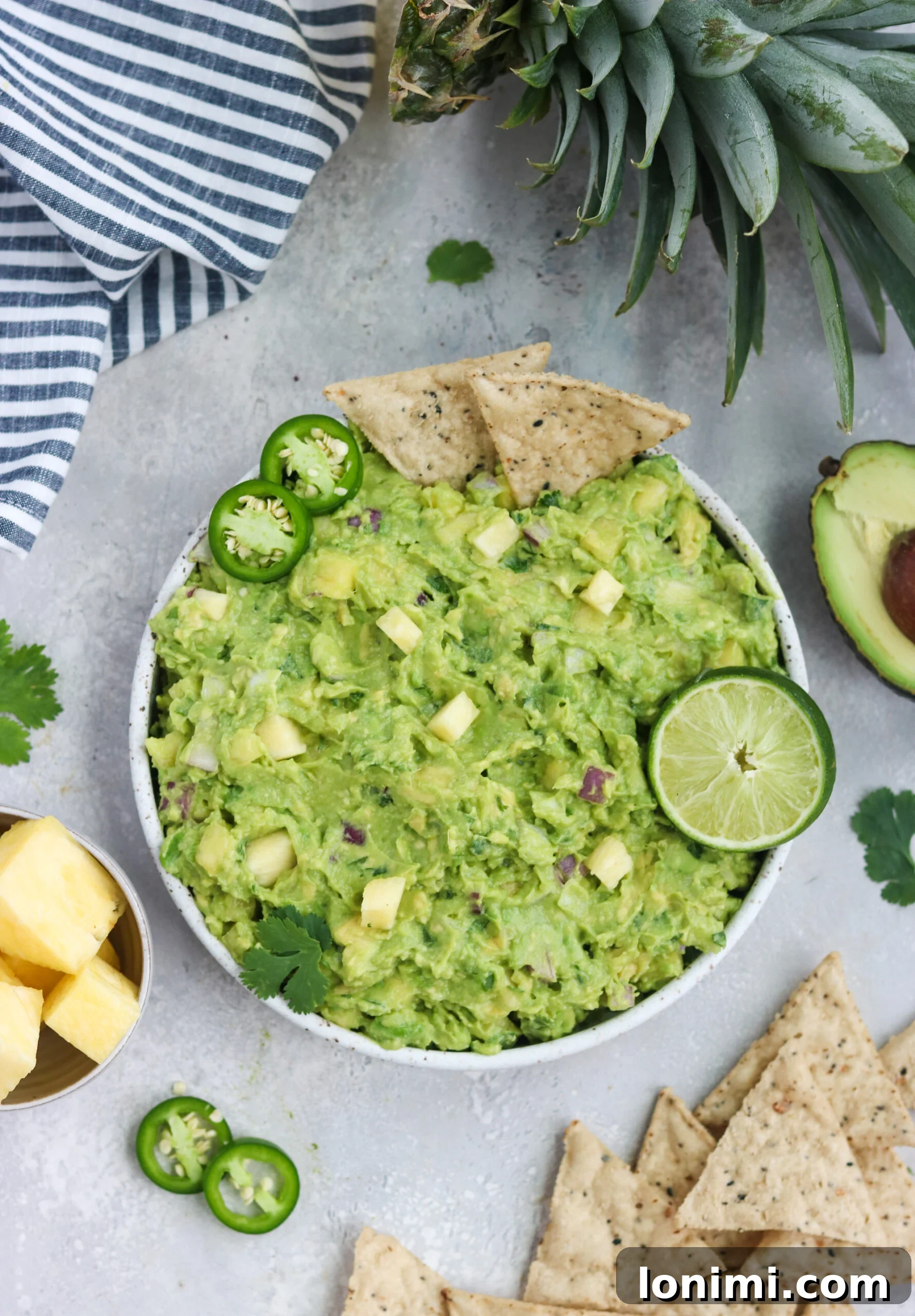 A vibrant bowl of pineapple guacamole with fresh lime and grain-free chips