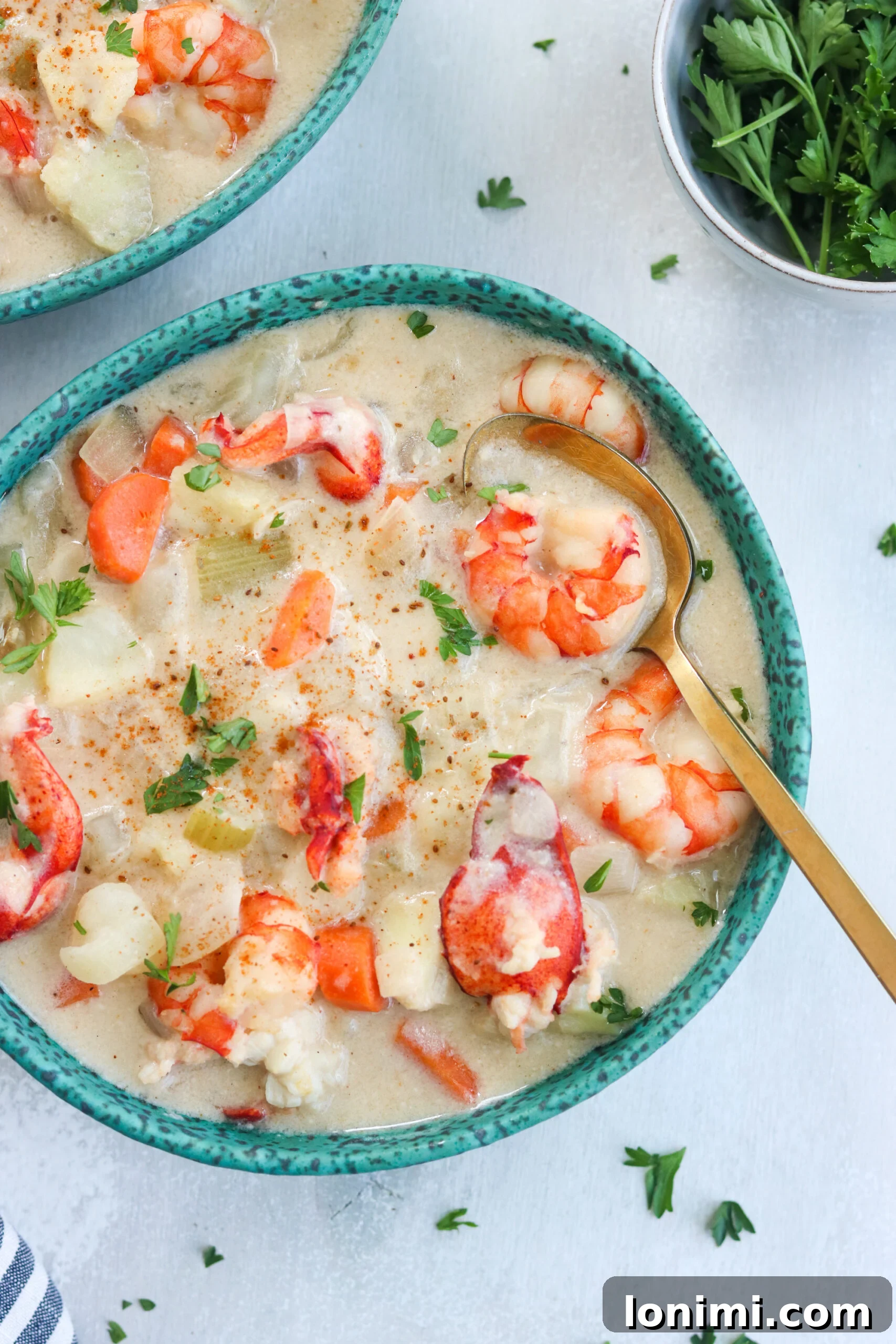 Delicious Paleo Seafood Chowder with a golden spoon A steaming bowl of creamy Paleo Seafood Chowder, garnished with fresh parsley and a golden spoon nestled within, highlighting its rich texture and generous seafood portions.