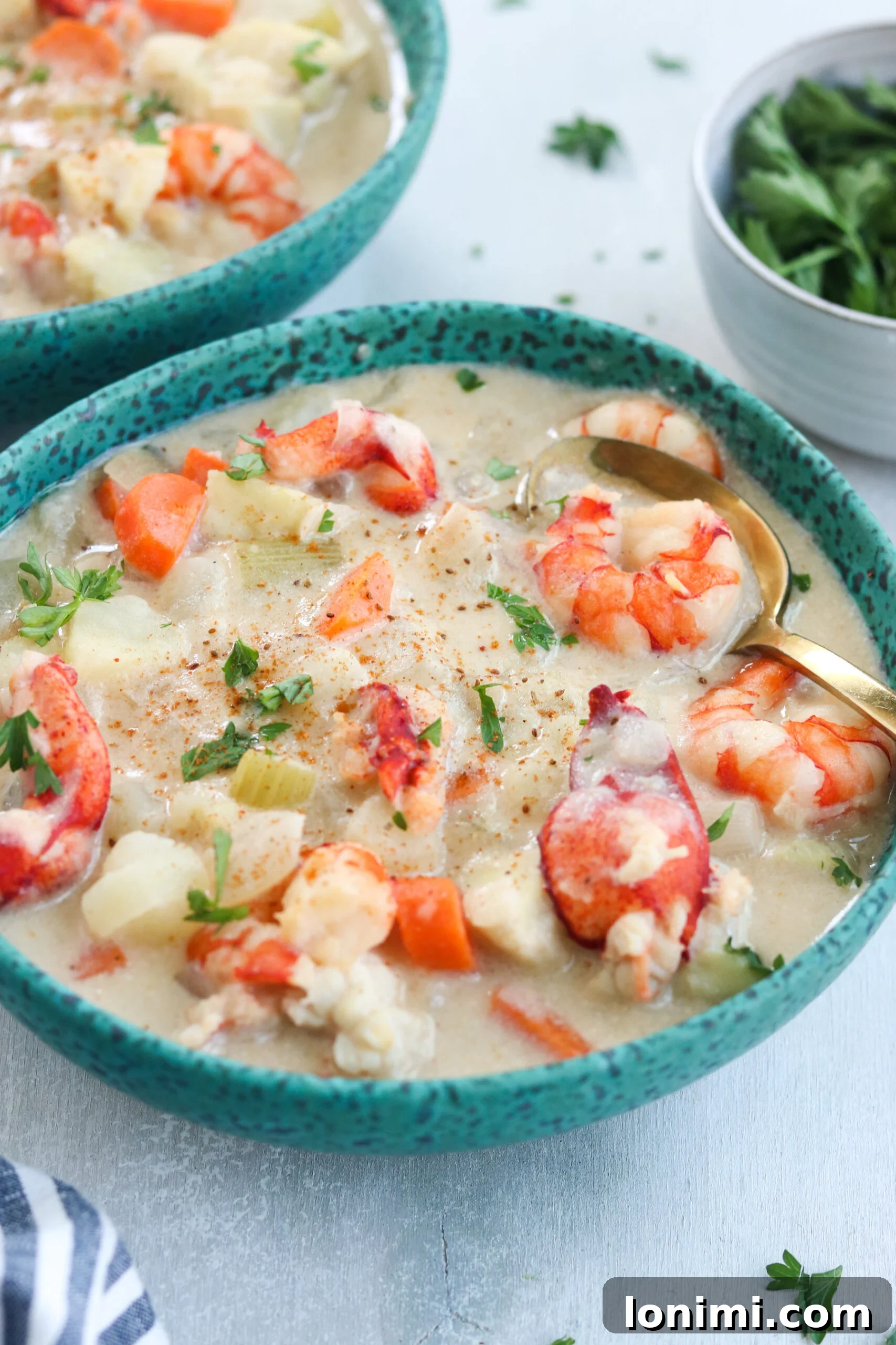 A comforting bowl of Paleo Seafood Chowder ready to be enjoyed Close-up of a bowl of Paleo Seafood Chowder, showing visible chunks of white fish, shrimp, and lobster, bathed in a creamy, golden broth and topped with fresh herbs.