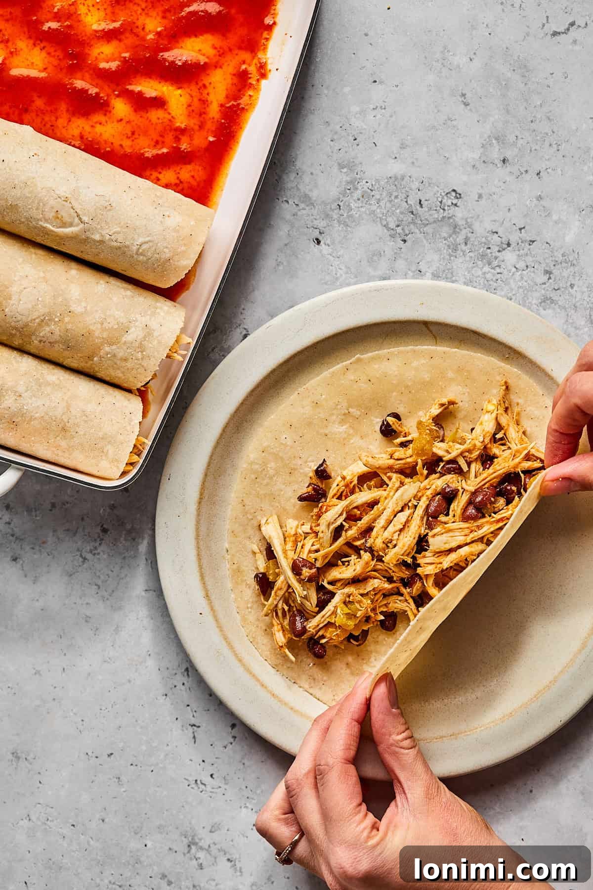 Weeknight Chicken and Black Bean Enchiladas 6 A single tortilla laid flat on a plate, generously filled with the chicken and black bean mixture, ready to be rolled into an enchilada.