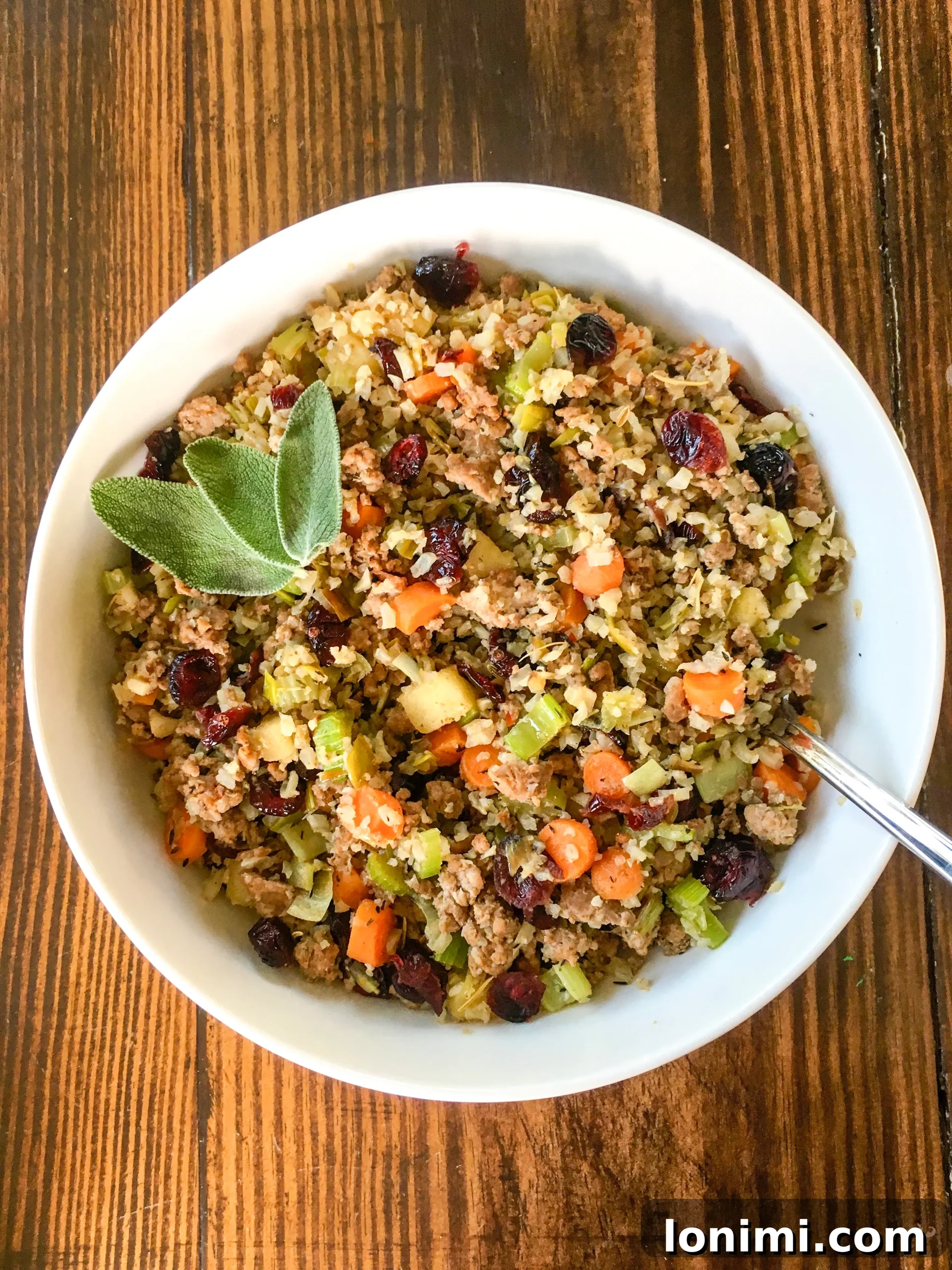 Savory Sausage Cauliflower Rice Stuffing Whole30 Keto Paleo 3 keto cauliflower stuffing in a white bowl garnished with fresh sage