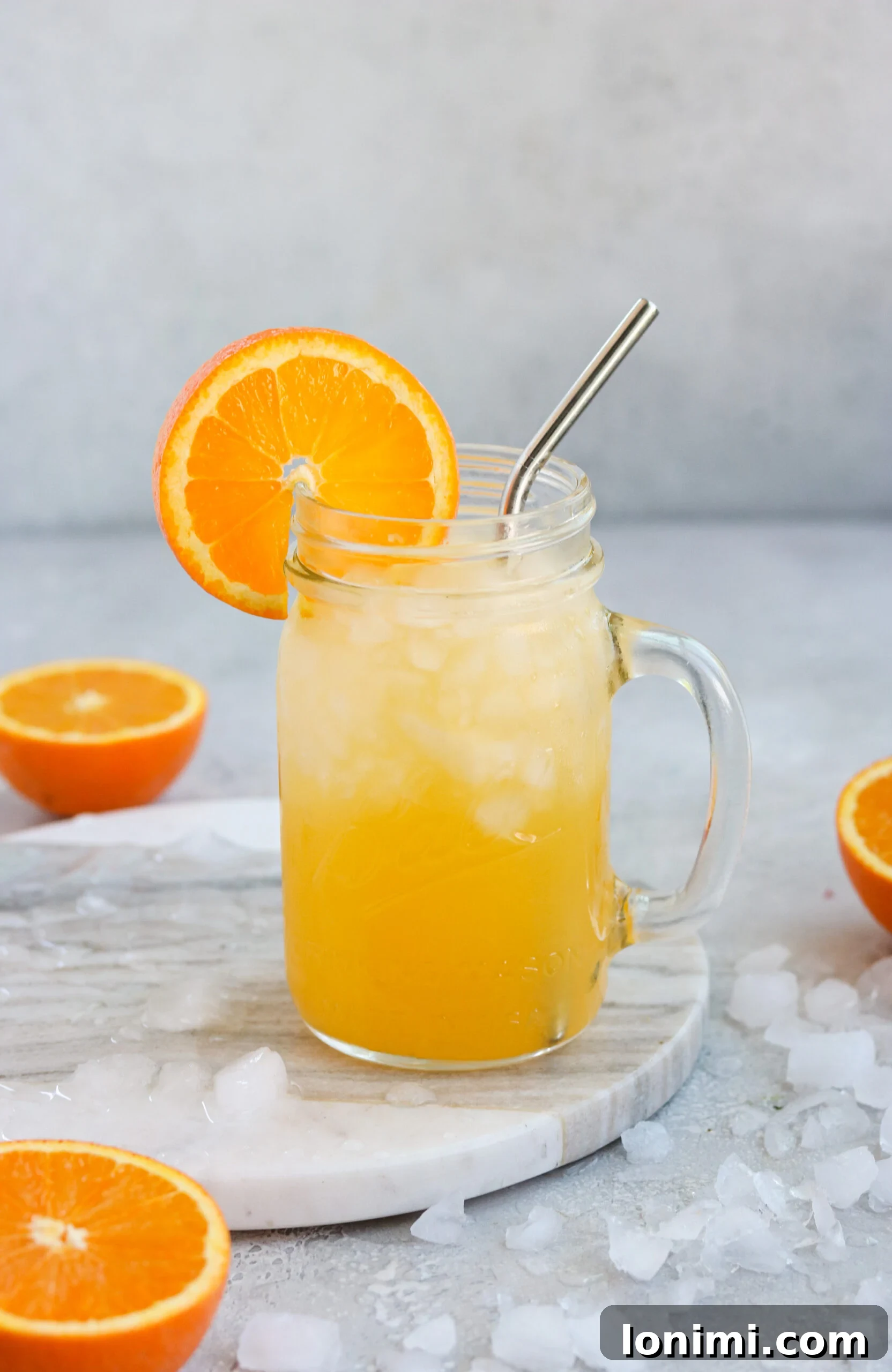 An inviting glass of orange cocktail surrounded by abundant crushed ice and vibrant sliced oranges, showcasing a perfectly chilled, refreshing drink.
