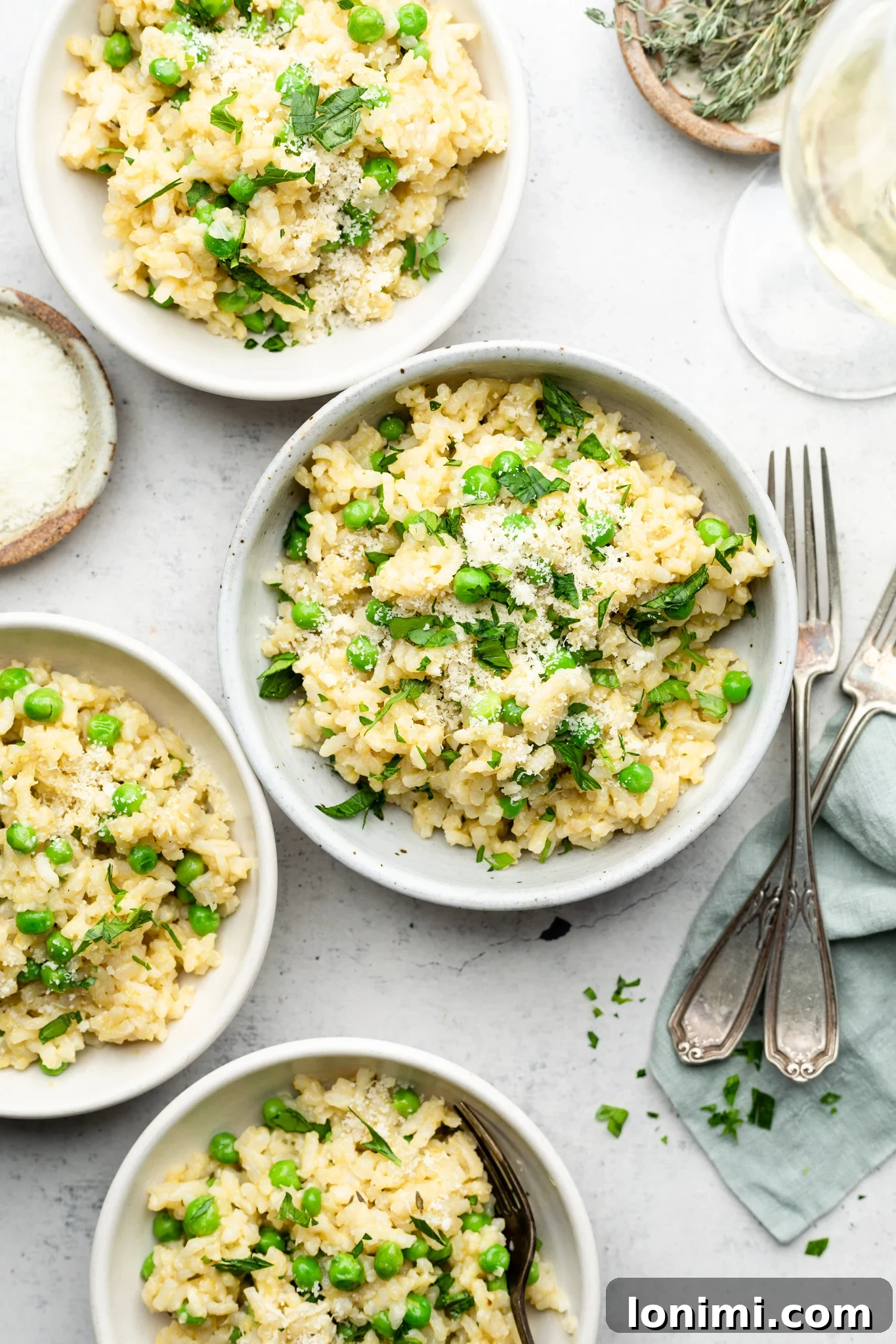Three elegant bowls of creamy Instant Pot Gluten Free Risotto with vibrant green peas, garnished with fresh herbs and a sprinkle of cheese.
