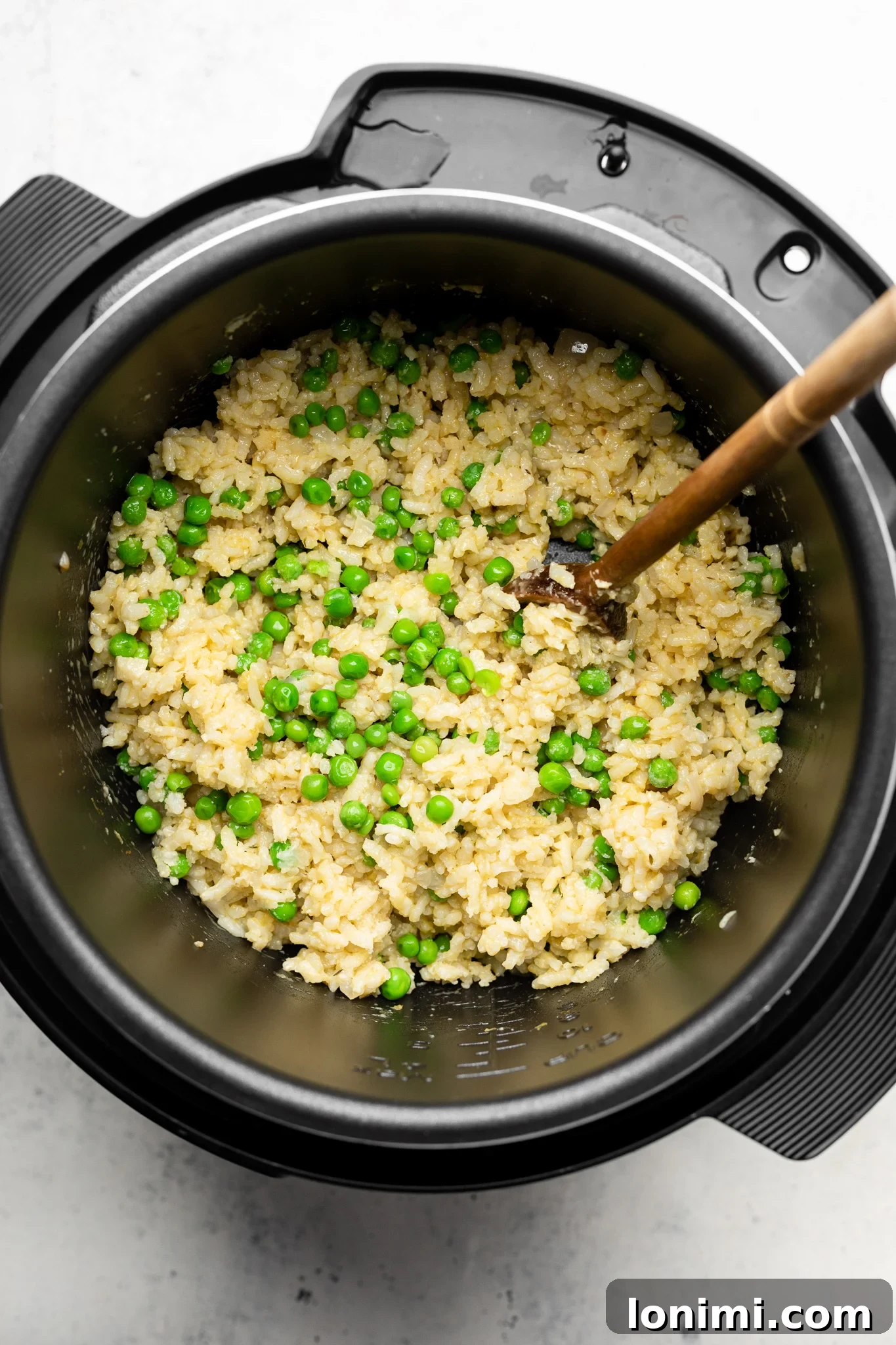 Close-up of Arborio rice and vibrant green peas simmering gently in an Instant Pot, ready to be transformed into creamy risotto.