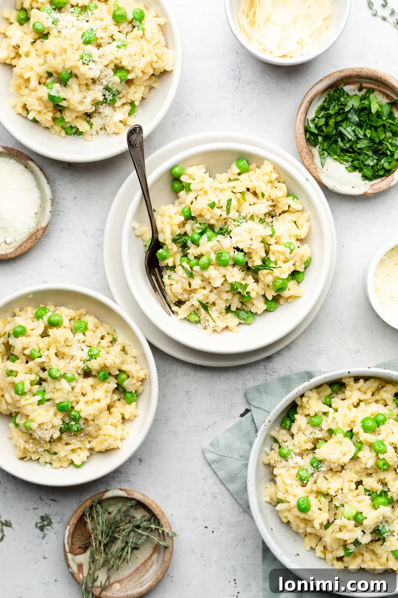 A selection of fresh ingredients laid out, including Arborio rice, fresh peas, broth, onions, garlic, and herbs, ready for making Instant Pot gluten free risotto.