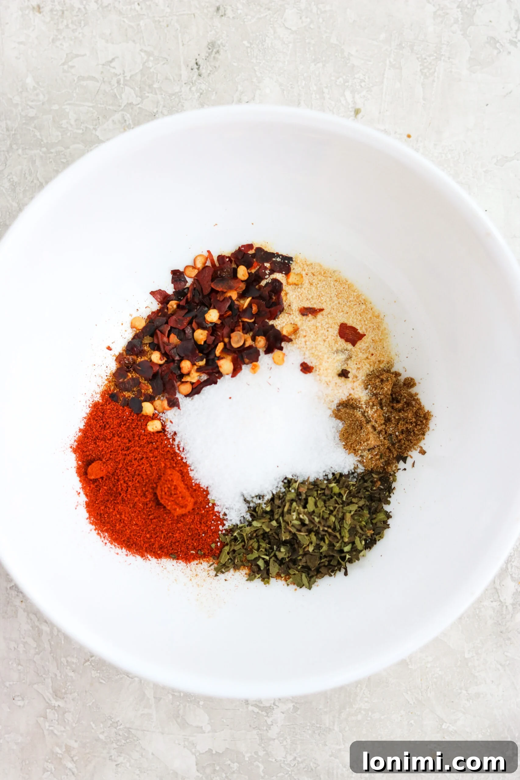 Homemade fajita spice mix in a small bowl with measuring spoons