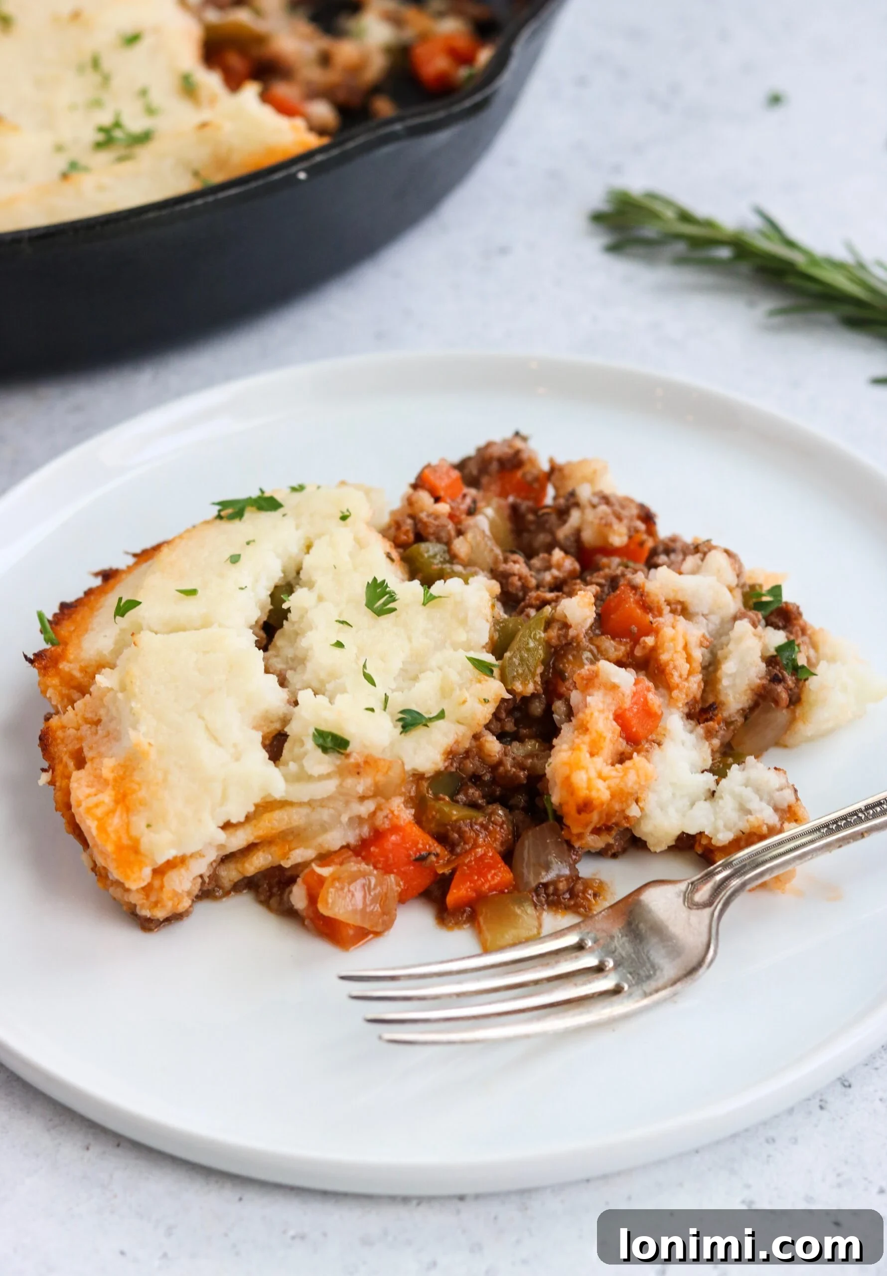 Whole30 + Keto Shepherd's Pie cooking in a cast iron skillet, ready for the oven with golden cauliflower topping