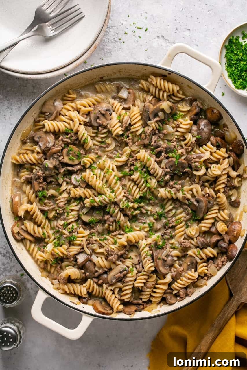 A steaming pot of homemade Hamburger Helper Stroganoff, garnished with fresh parsley, ready to serve.