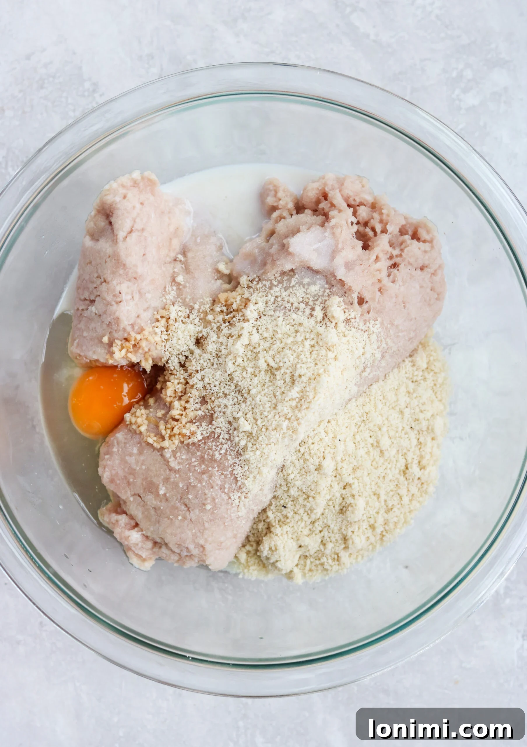 Baked Paleo Butter Chicken Bites 2 prepping ground chicken with ingredients in a clear glass mixing bowl