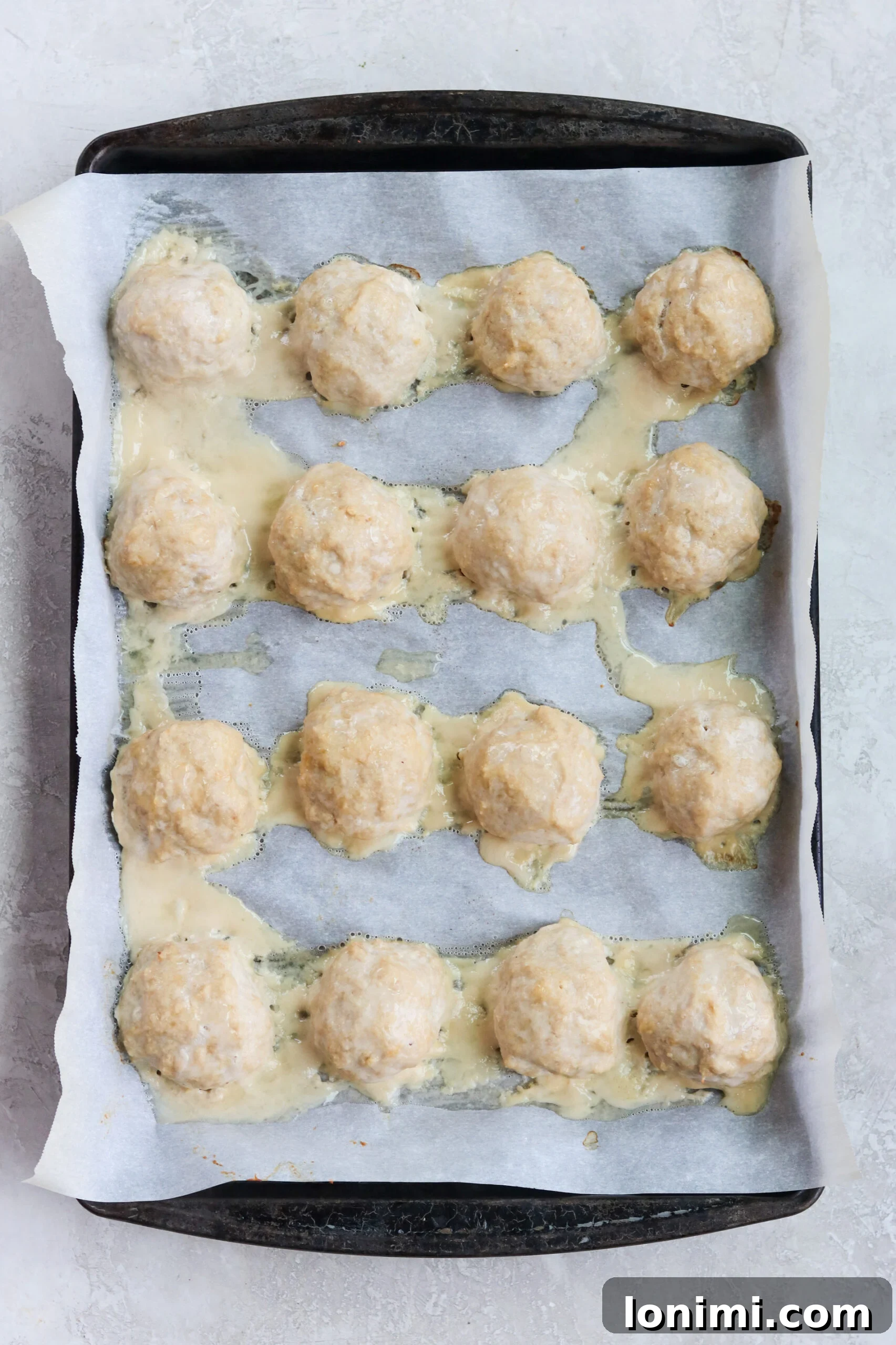 Baked Paleo Butter Chicken Bites 3 ground chicken meatballs with no breadcrumbs on a baking sheet with parchment paper