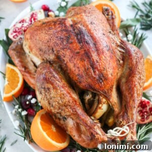 Paleo Roasted Turkey with oranges and pomegranates and herbs on a white platter