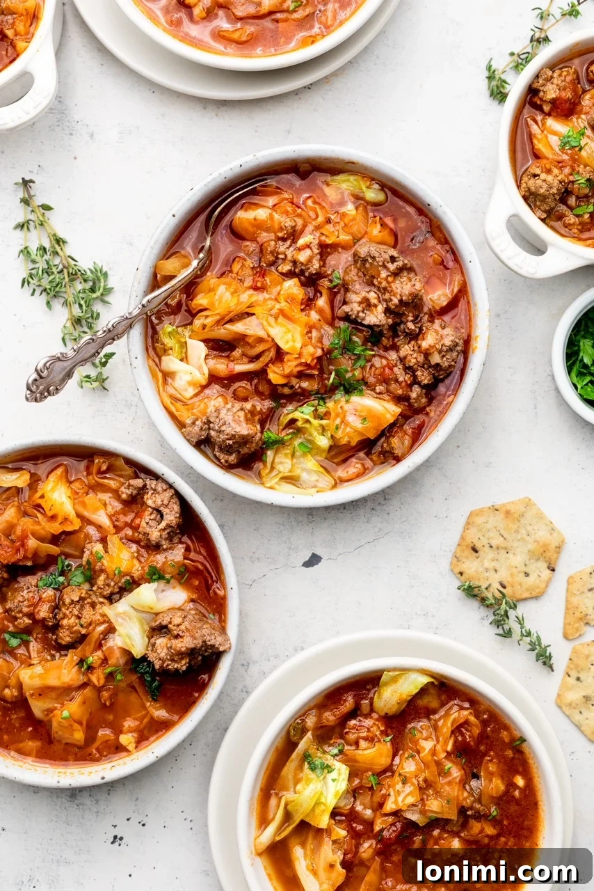 Three bowls of hearty unstuffed cabbage soup, garnished with fresh herbs and served with crackers on the side, ready to be enjoyed.
