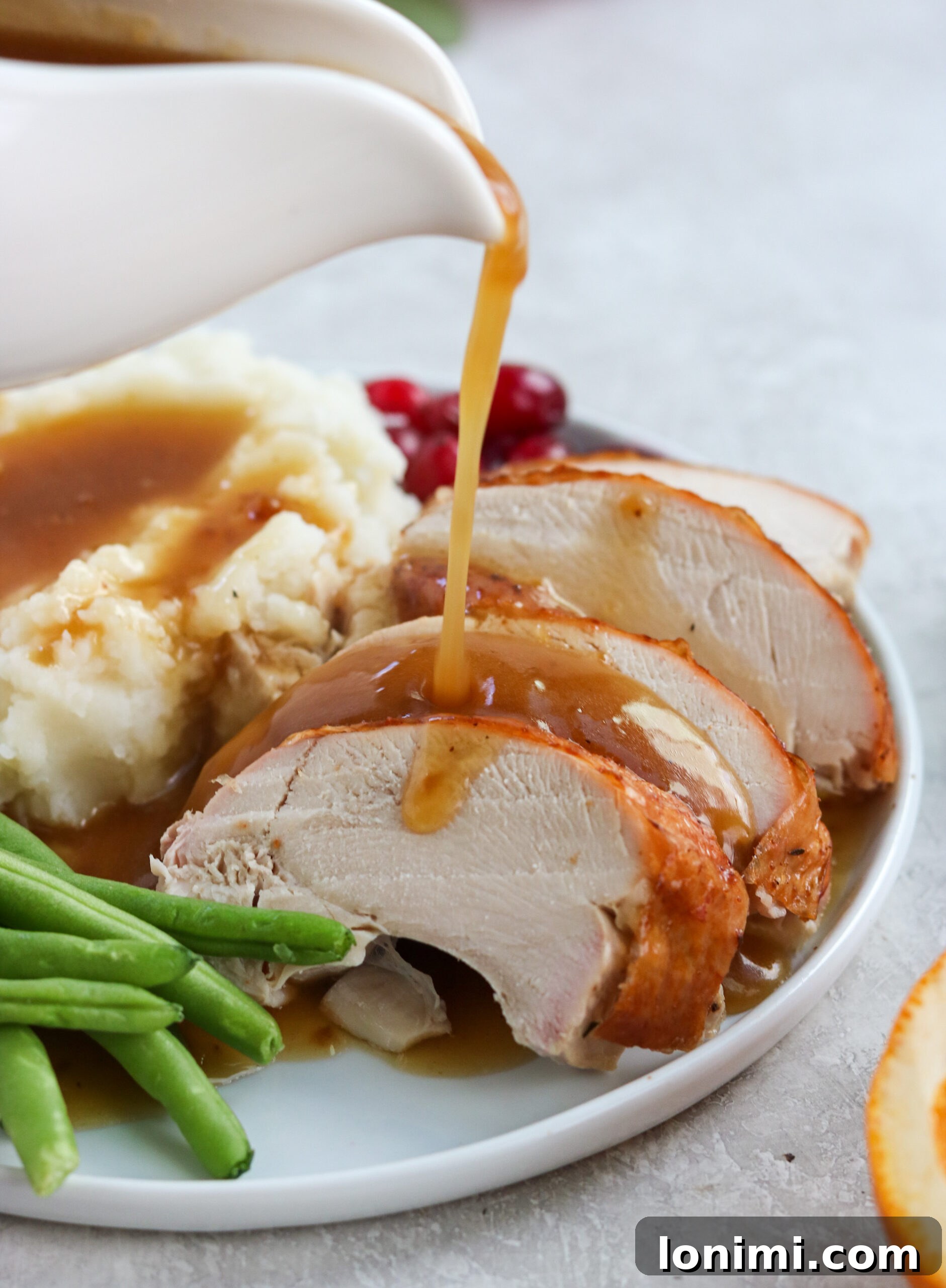 A pristine white gravy boat elegantly pouring a stream of luscious homemade gluten-free gravy over a beautifully roasted turkey, making for an inviting and classic holiday presentation.