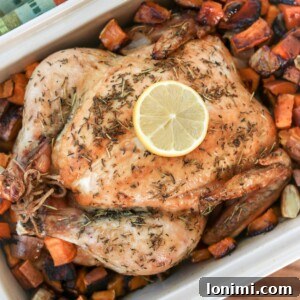 A close-up of a carved roasted chicken piece alongside vibrant roasted root vegetables in a serving dish, highlighting the juicy interior of the chicken and the golden vegetables.