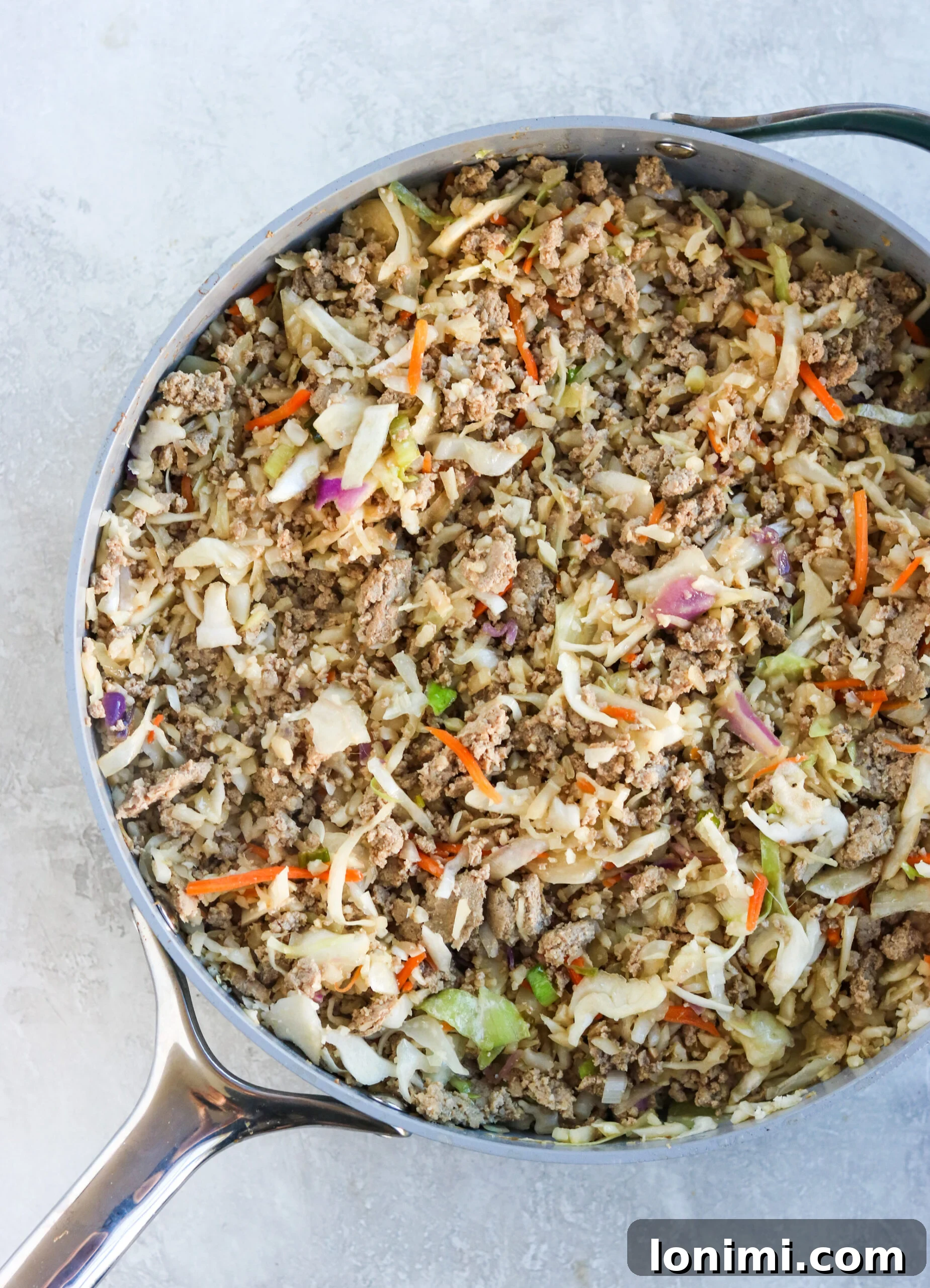 The deliciously cooked keto egg roll in a bowl mixture, still sizzling, served directly in a large cast-iron skillet, showcasing its rustic and comforting appeal, ready for serving.