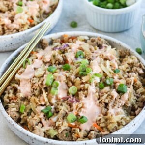 Healthy egg roll in a bowl with green onions and gold chopsticks