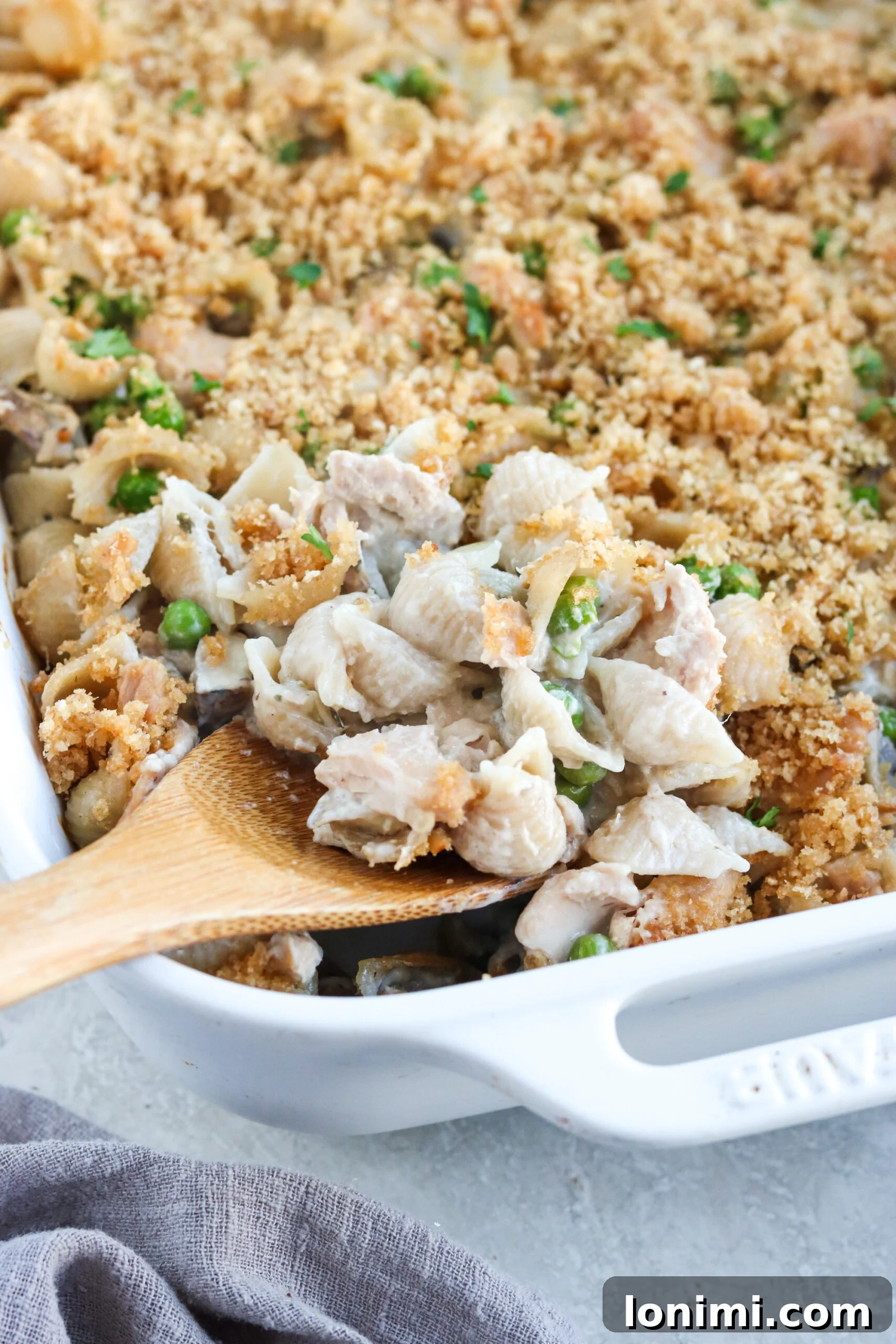 Wholesome Tuna Noodle Bake 2 Gluten Free Tuna Casserole with peas and mushrooms in a white casserole dish, garnished with fresh parsley.
