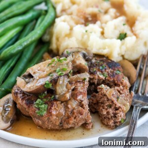 Grandma's Comfort Salisbury Steak with Savory Mushroom Gravy 13 Salisbury steak with mashed potatoes and green beans on a white plate