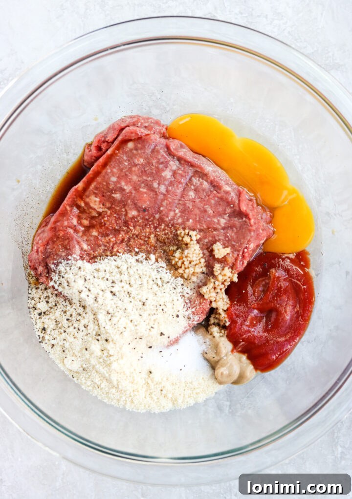 Grandma's Comfort Salisbury Steak with Savory Mushroom Gravy 4 Ground beef mixture being combined in a clear glass mixing bowl for Salisbury steak