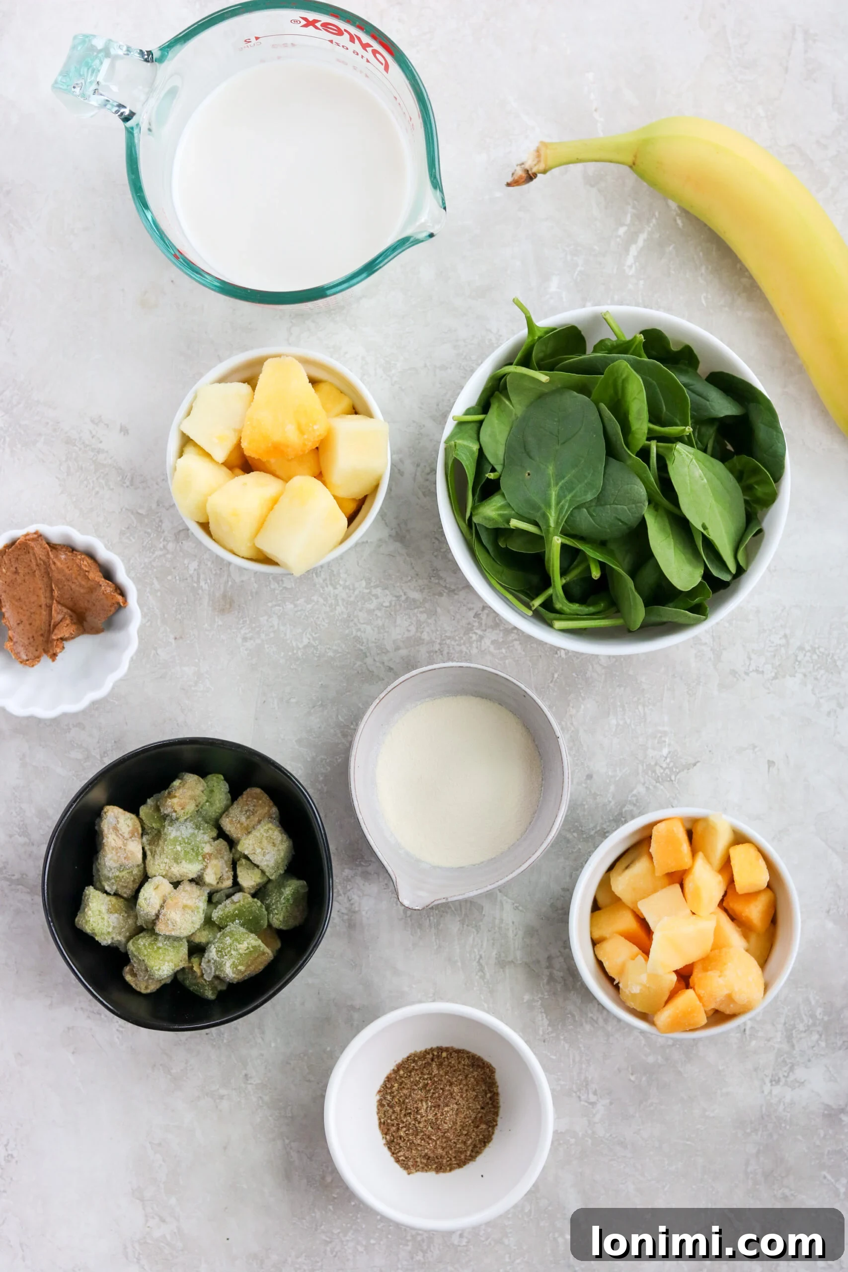 Fresh ingredients laid out for making a tropical green smoothie, including spinach, mango, pineapple, and avocado.