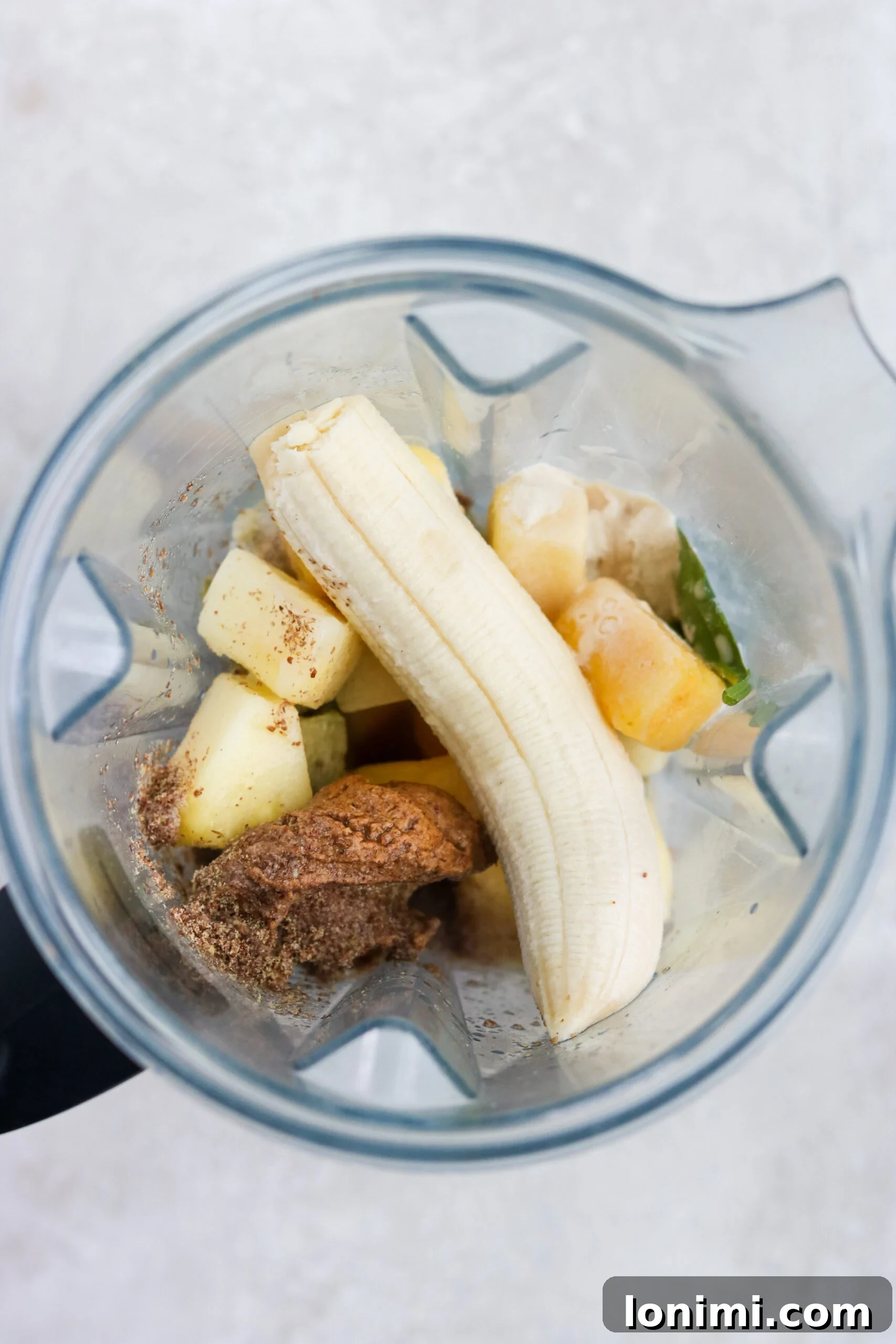 A selection of whole ingredients for a Green Goddess Smoothie, including spinach, bananas, mango, and avocado, illustrating the freshness of the components.