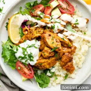 Sheet Pan Chicken Shawarma Bowl with cauliflower rice, tomatoes, parsley, lemon, tzatziki, and lemon tahini dressing