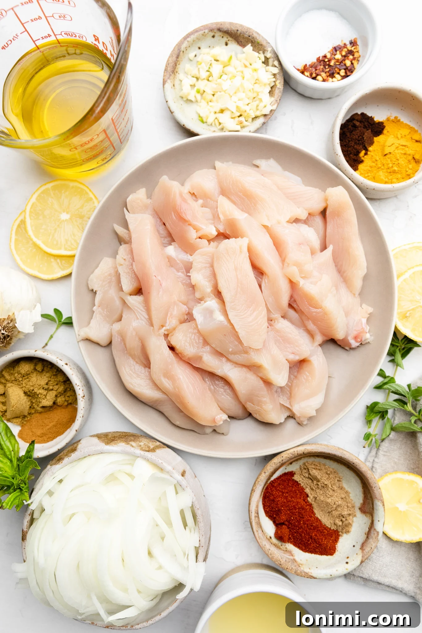 A vibrant selection of fresh ingredients including thinly sliced chicken, an array of spices, onions, garlic, and lemon, prepared for making homemade chicken shawarma.