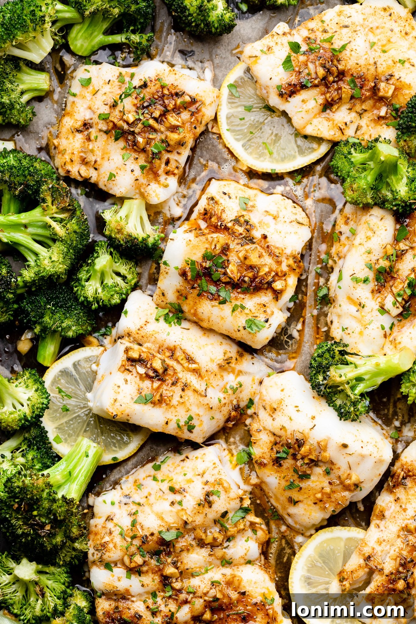 Cajun butter cod and broccoli on a sheet pan, ready to be baked