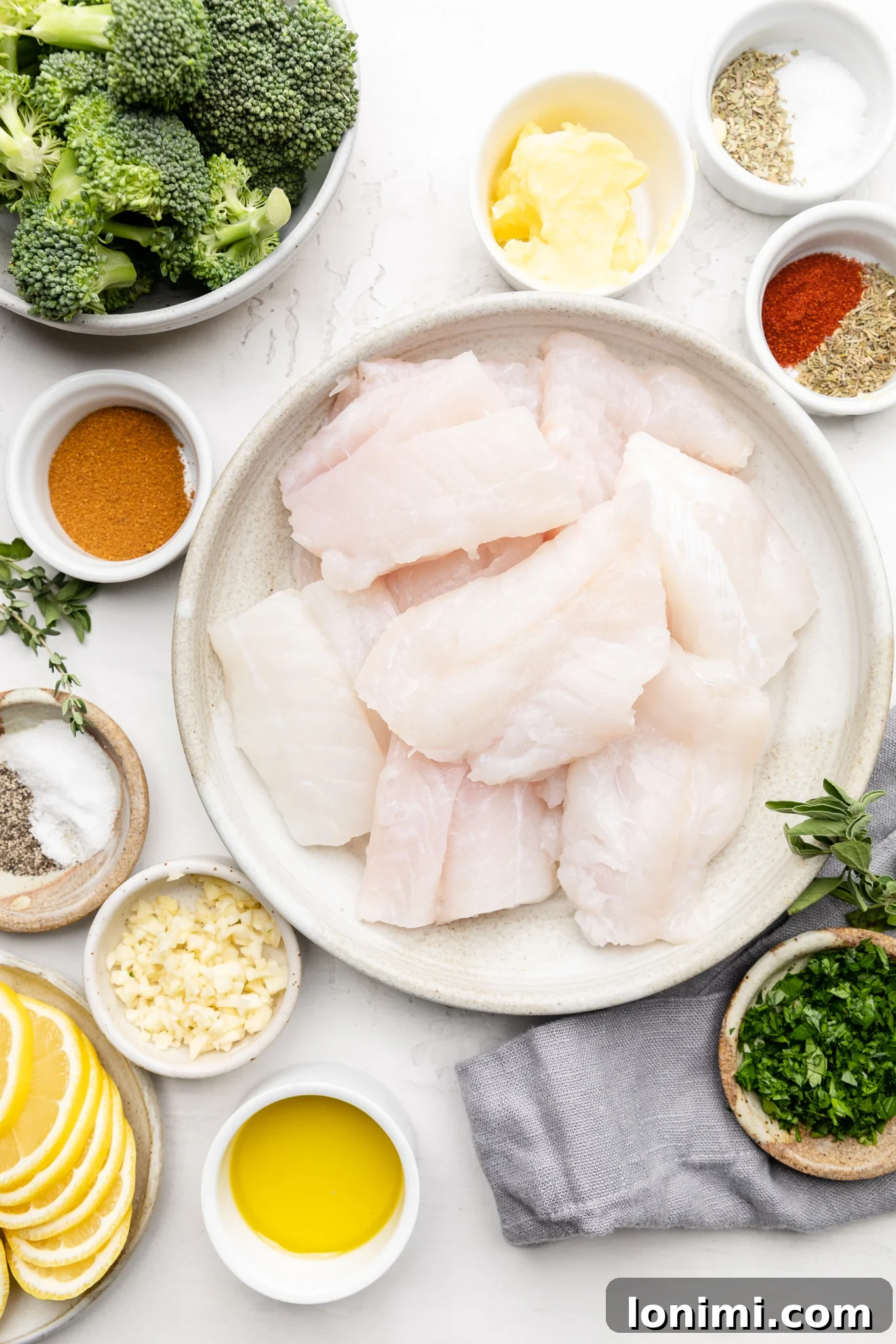 Ingredients laid out to make seafood boil sauce and cajun cod, including spices, garlic, butter, cod, and broccoli
