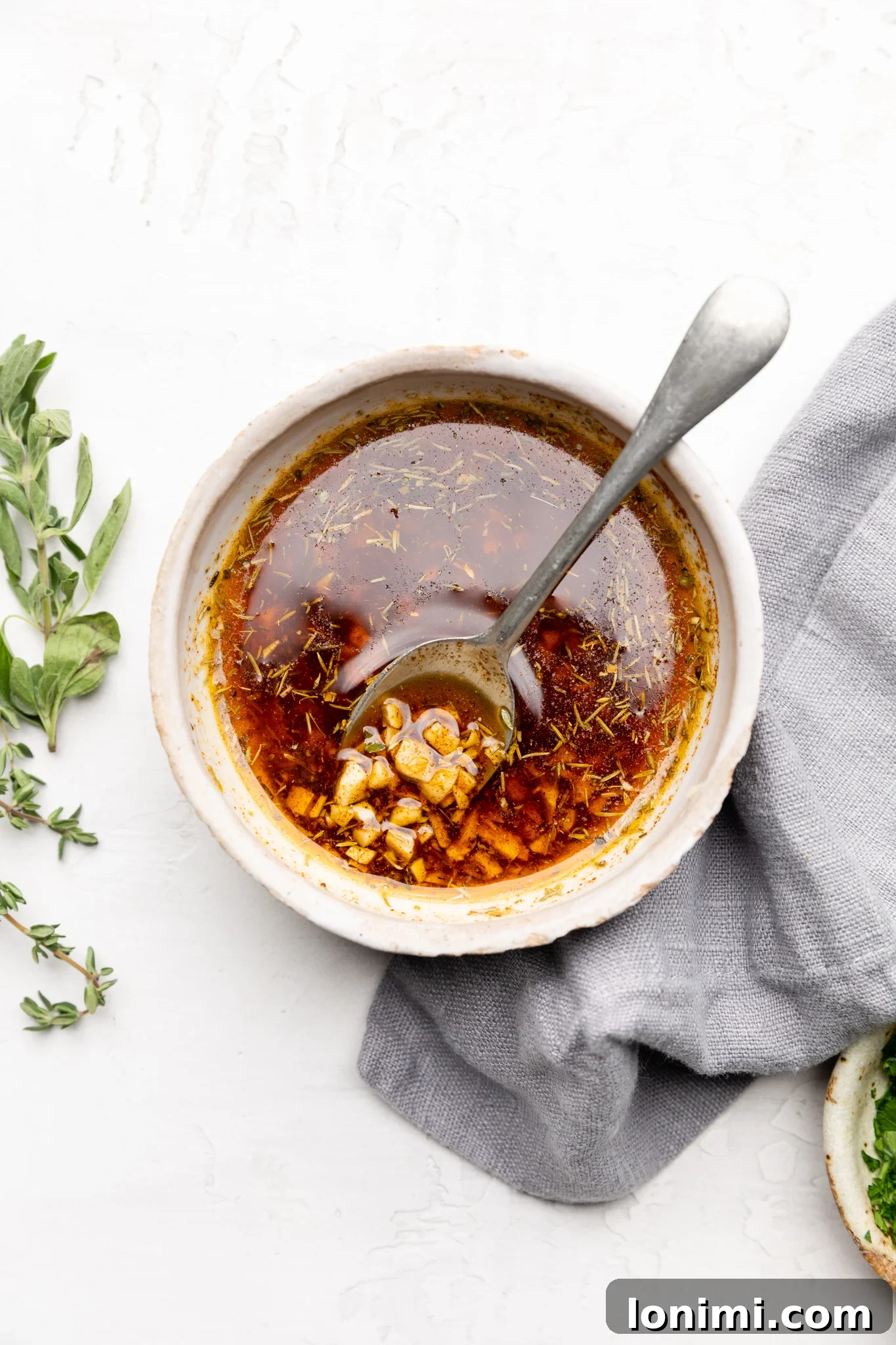 Cajun butter sauce in a white bowl with a silver spoon, ready to be poured