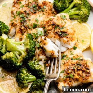 Sheet Pan Cajun Butter Cod with Broccoli on a plate with lemons and a fork