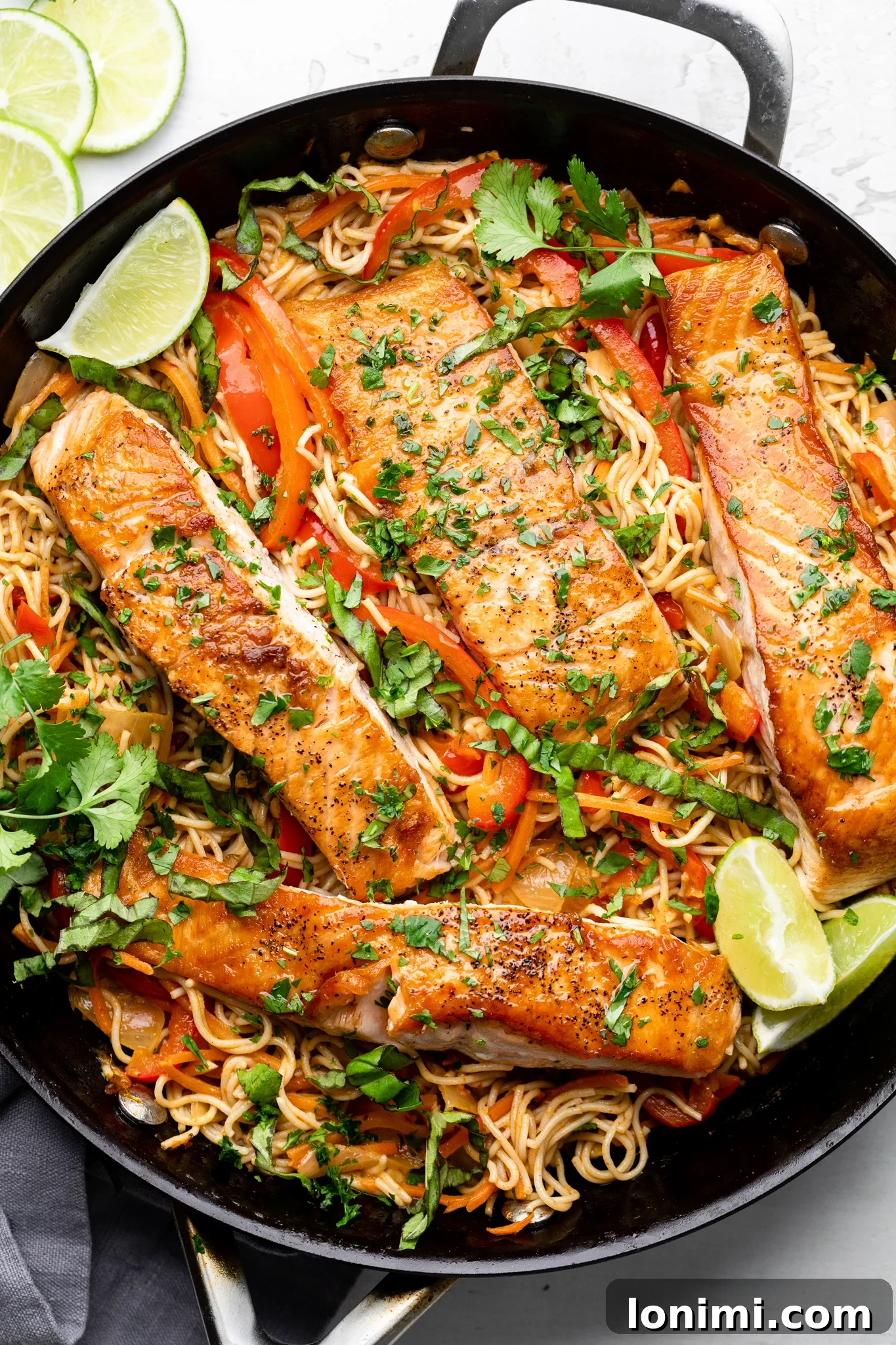Gluten-free ramen noodles with Thai curry salmon in a black skillet, ready to serve