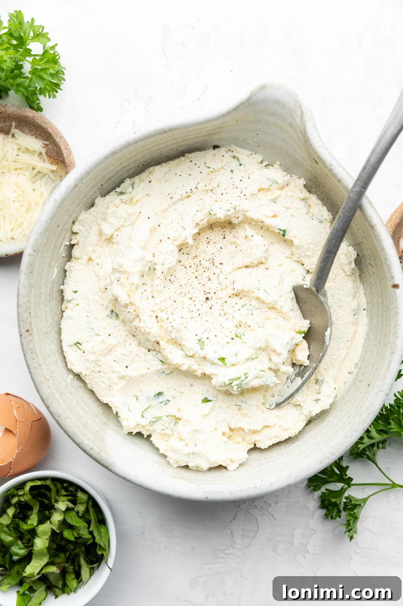 Effortless Allergen-Friendly Lasagna 5 A creamy mixture of dairy-free ricotta cheese, egg, and fresh herbs in a gray bowl, ready for layering