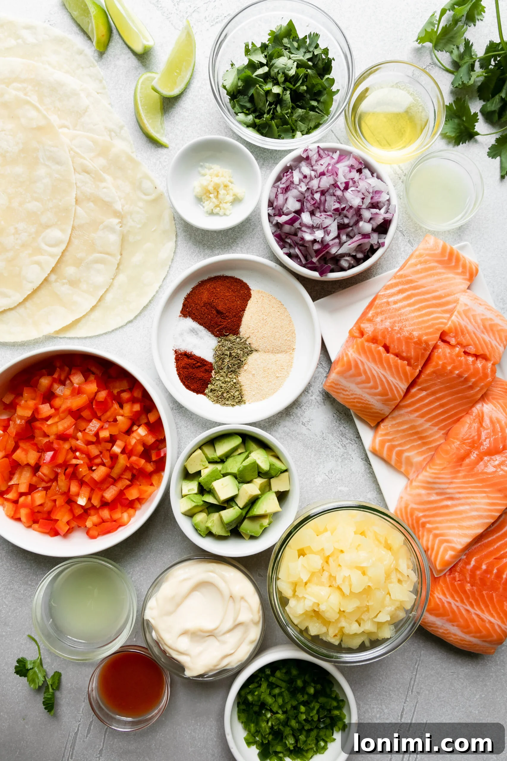 Tropical Blackened Salmon Tacos 3 glass bowls filled with ingredients next to lime wedges and gluten free tortillas