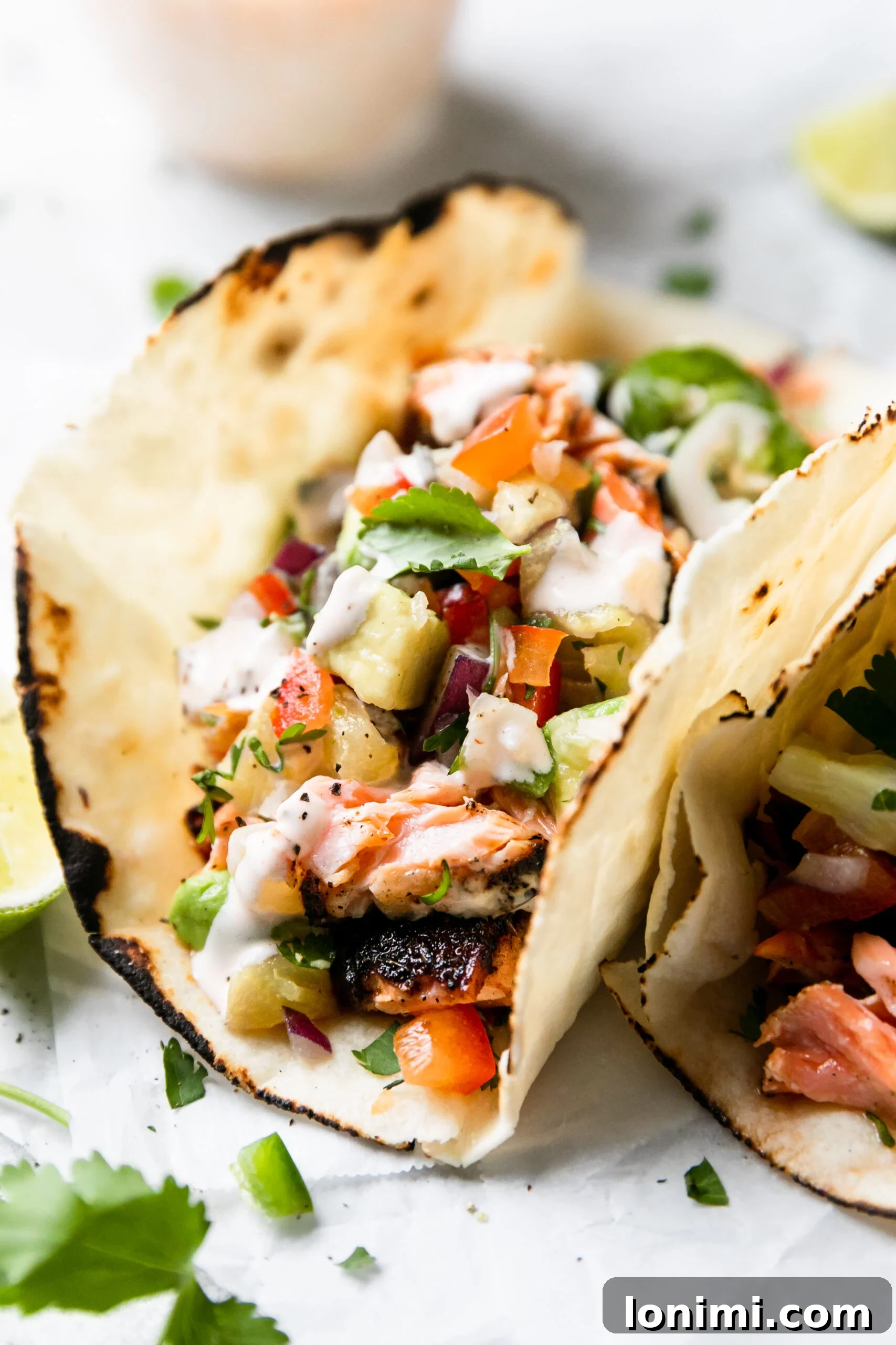 Tropical Blackened Salmon Tacos 6 a closeup of two blackened salmon tacos folded