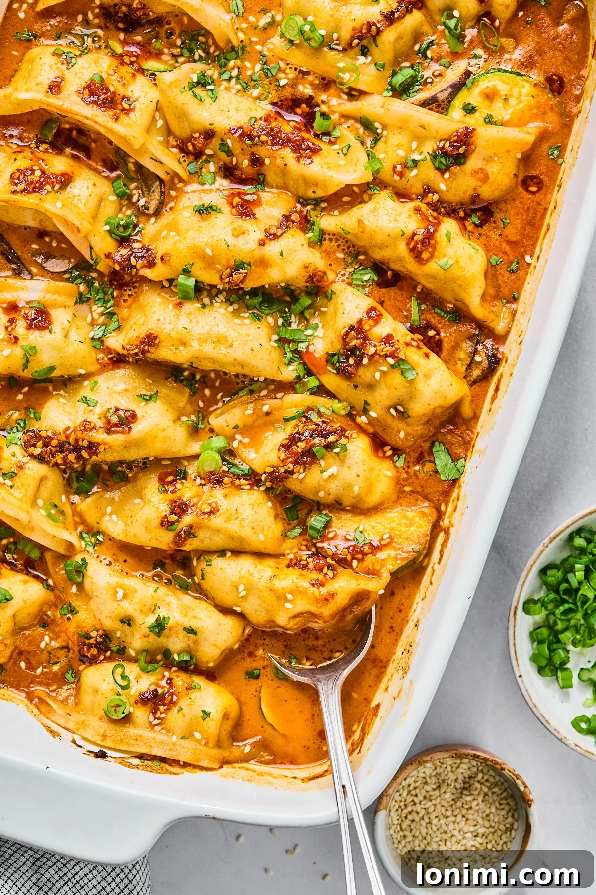 Gluten Free dumplings baked in a casserole dish with a red sauce topped with cilantro and green onions