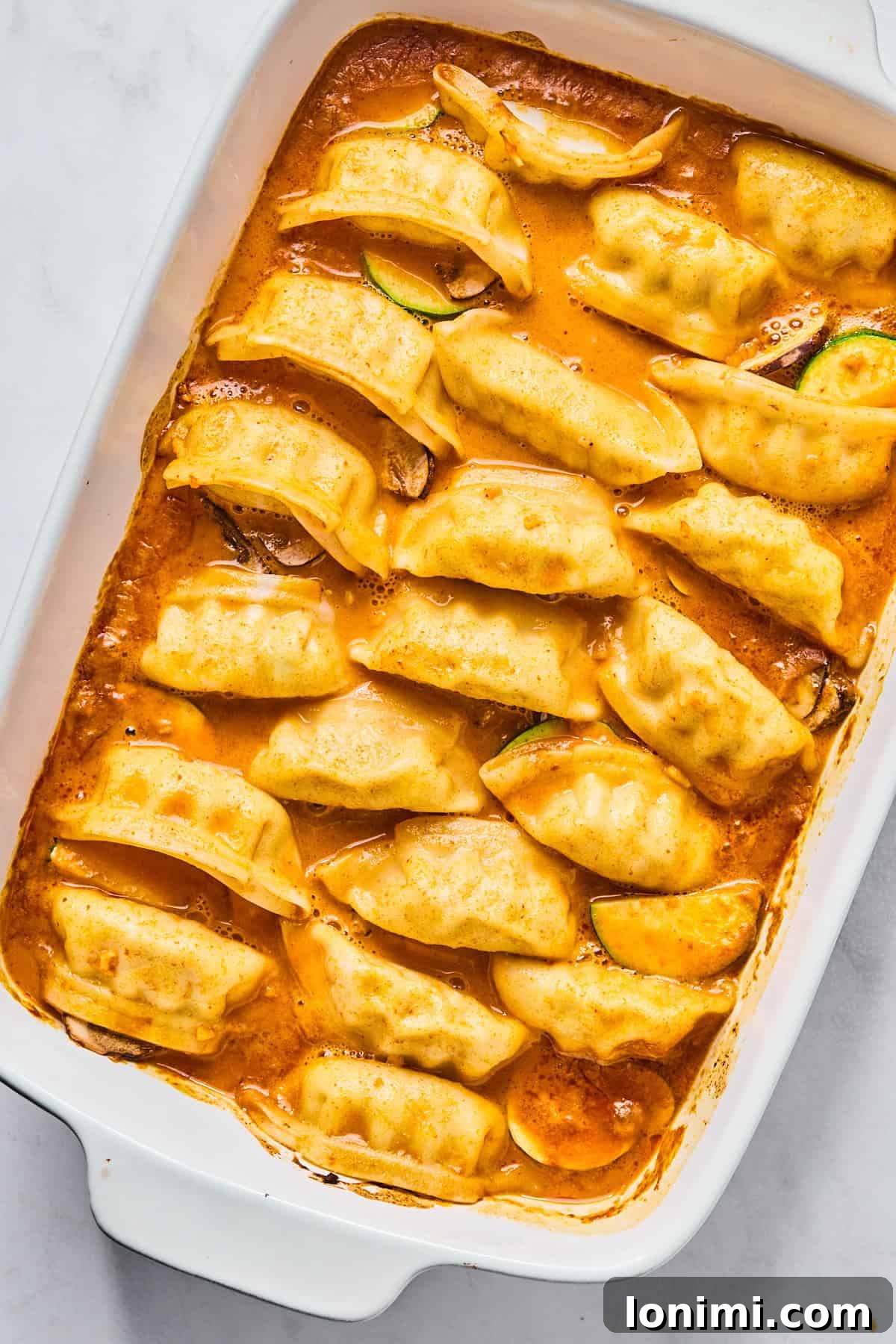 Potstickers baked in a sauce in a casserole dish