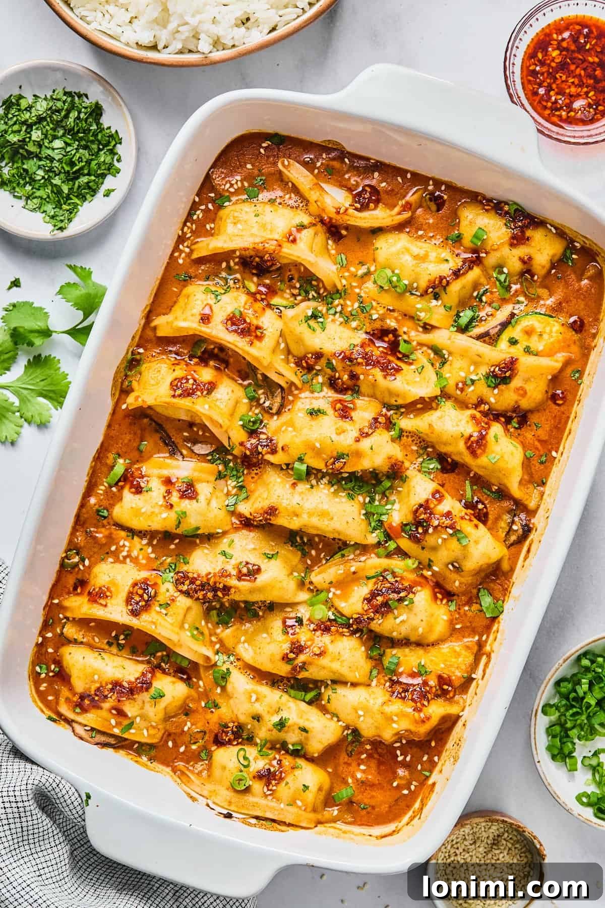 the viral dumpling bake in a casserole dish topped with cilantro and green onions and chili crunch