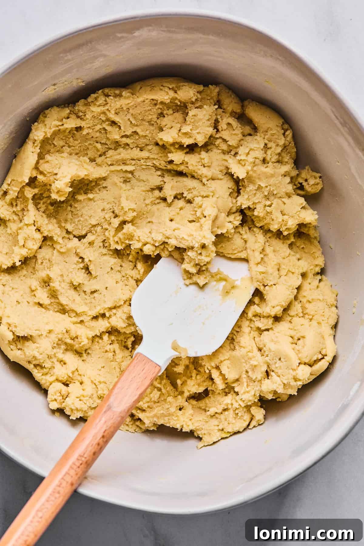 Gluten-free Italian wedding cookie dough resting in a large bowl, indicating it has just come together and is ready for the next step.