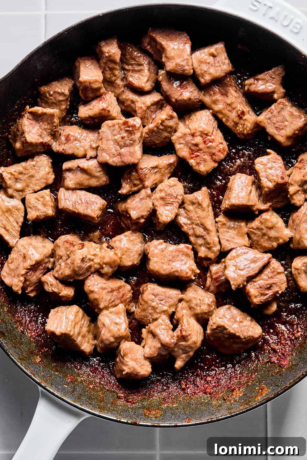 Stew meat in a skillet seared on all sides, achieving a rich brown color for deep flavor.