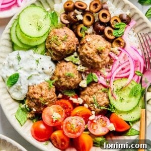 Easy Greek Lamb Meatballs with Zesty Lemon Dill Yogurt 12 Greek lamb meatballs in a bowl with veggies and lemon dill feta sauce