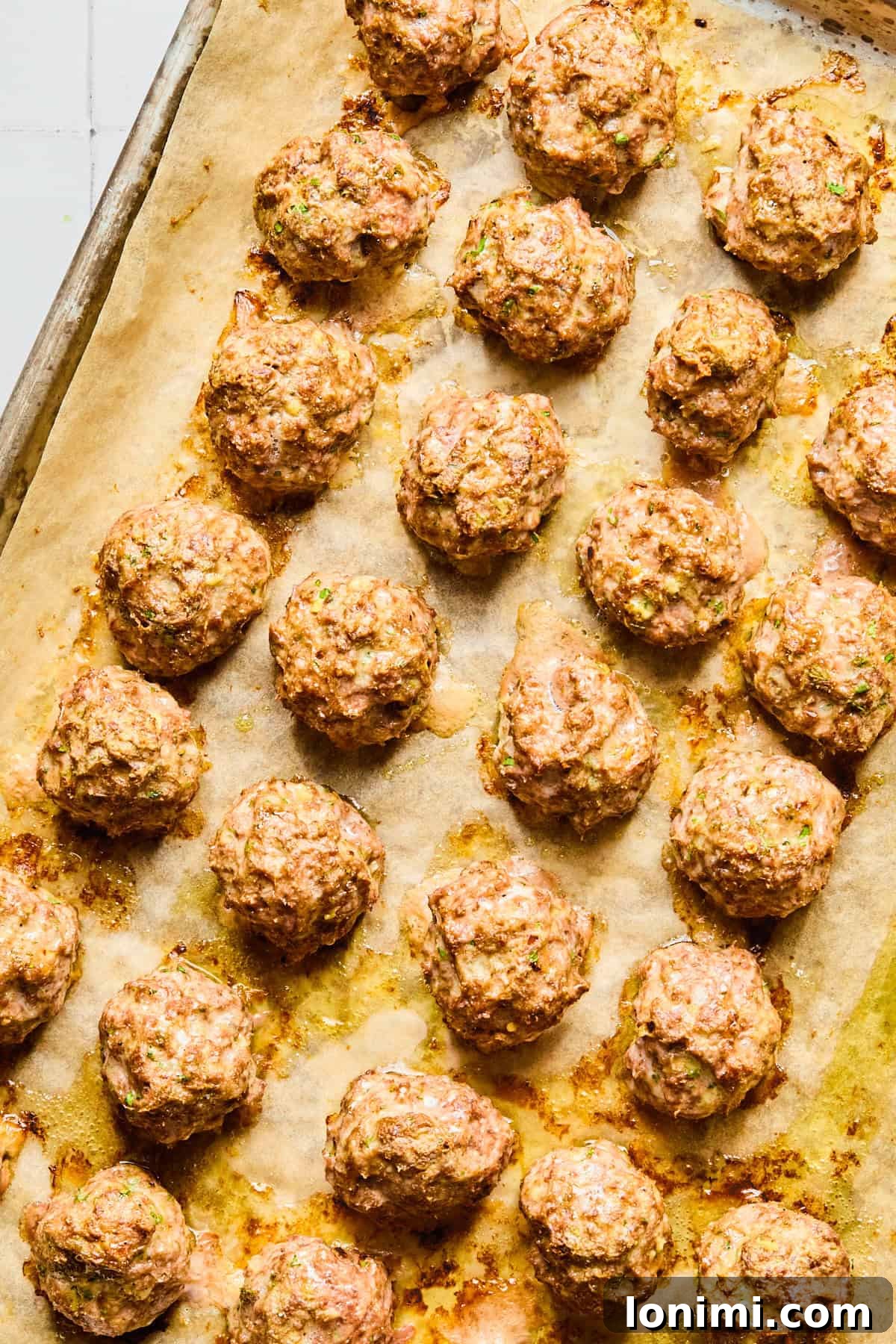 Easy Greek Lamb Meatballs with Zesty Lemon Dill Yogurt 7 Lightly browned Greek lamb meatballs on a parchment-lined baking sheet.